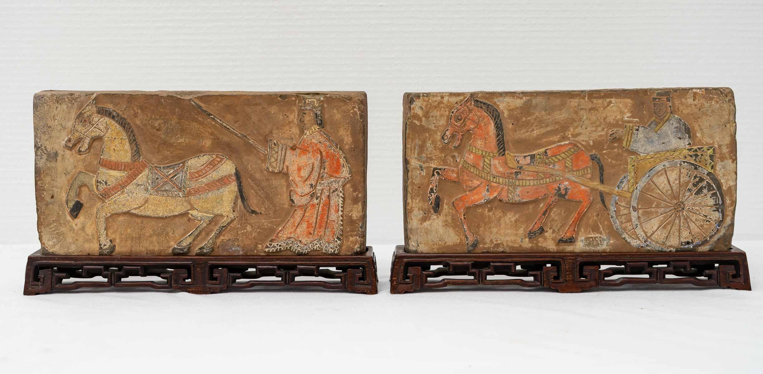 Pair of terracotta bricks with traces of polychromy representing for one a character driving his chariot drawn by a horse and for the other a character training his horse.

These two bricks are exposed on their original carved wooden bases.

Period