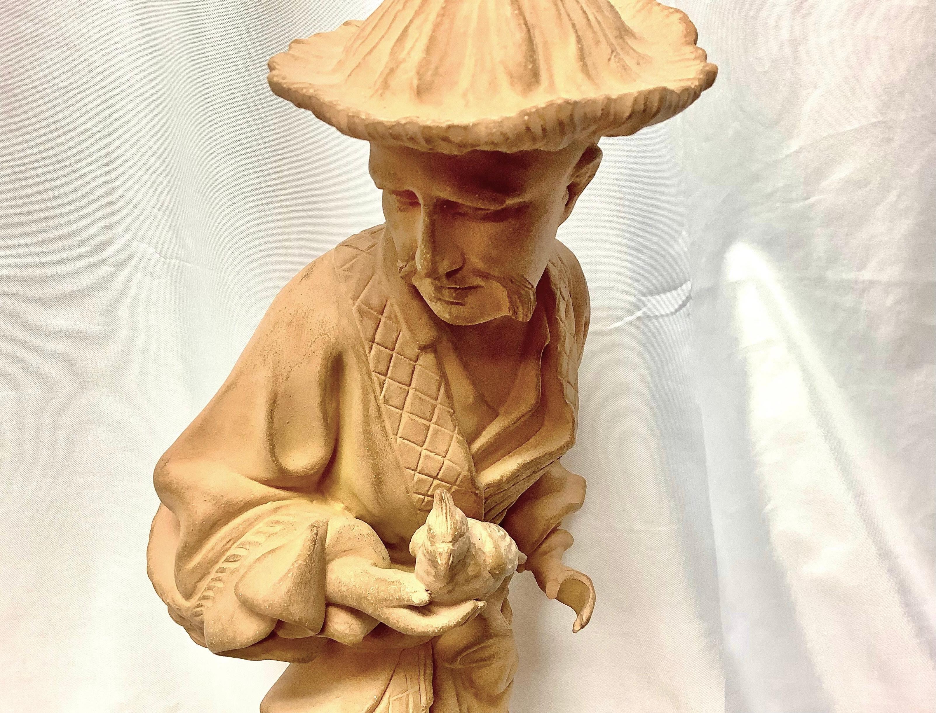 Unique pair of terracotta Chinoiserie Chinese figures. Man is holding a bird, woman is holding a lantern. Excellent condition.