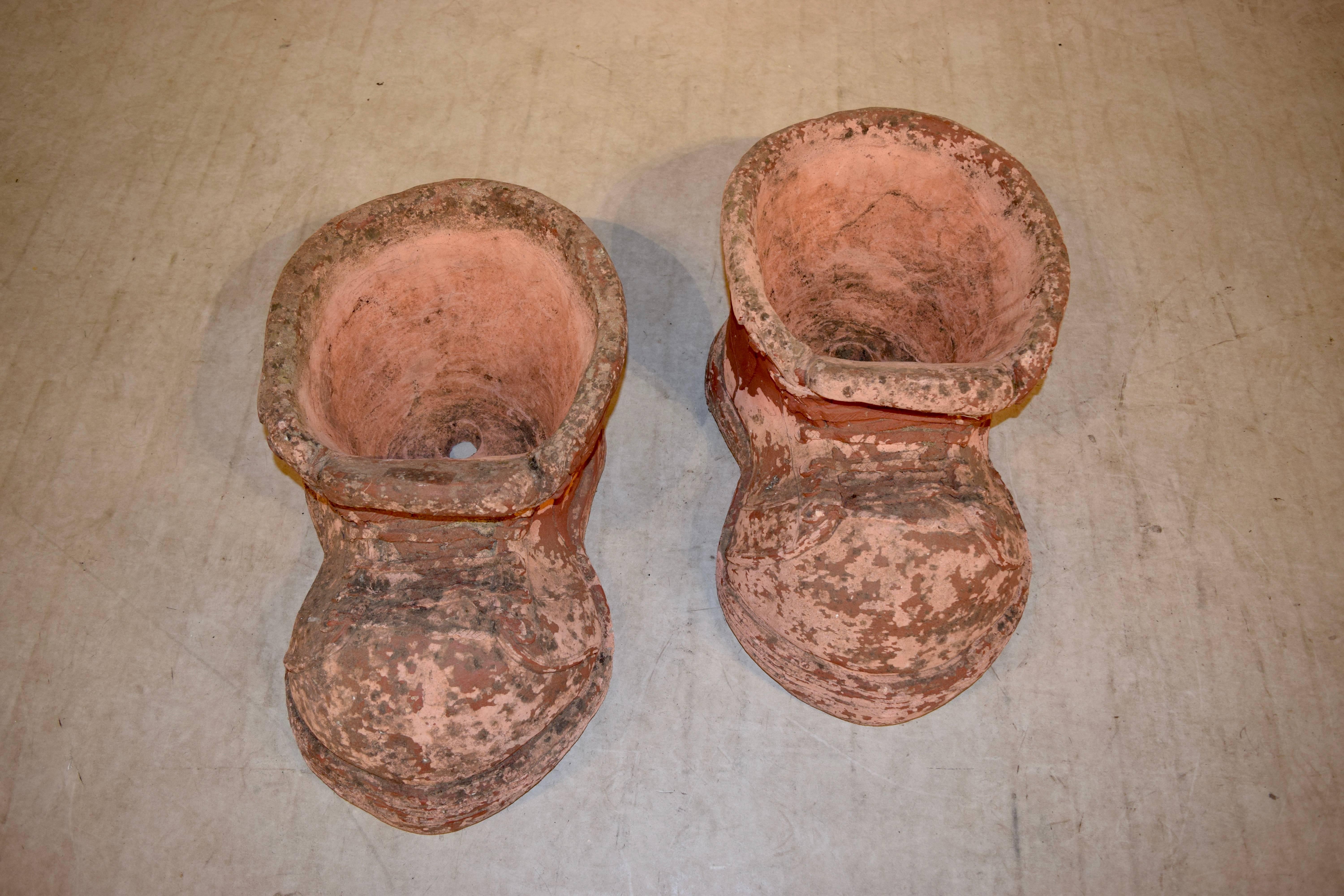 Ein Paar große Terrakotta-Pflanzgefäße in Form eines Paares Schuhe.
