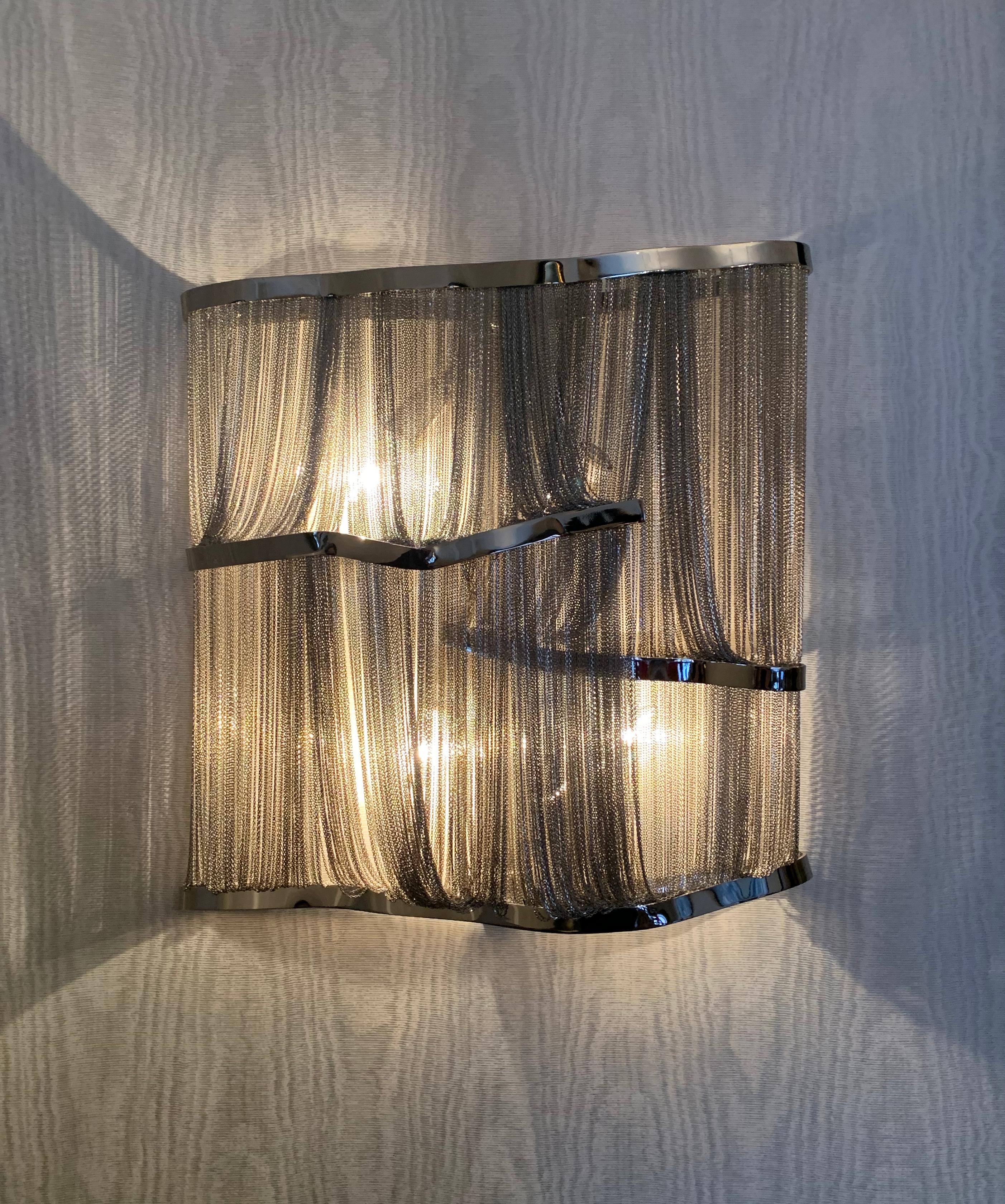 A pair of modern wall lights in black nickel metal. Designed by Barlas Baylar for Terzani Lighting, Italy. 

Created as part of the iconic 'Atlantis collection' The wall lamps are made from  solid metal components which delicately hold swathes of