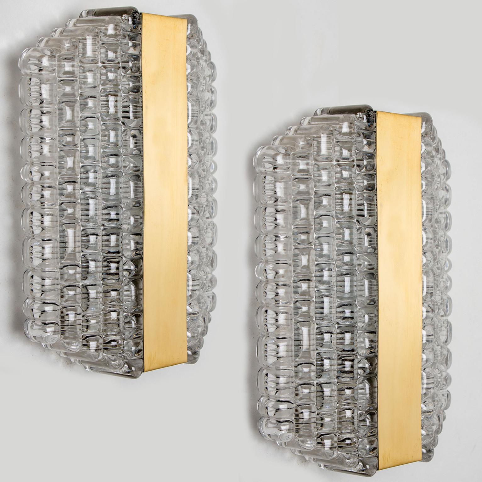Pair of handmade high quality light fixture made by Kaiser Leuchten, Austria. Manufactured in midcentury, circa 1970 (at the end of 1960s and beginning of 1970s).
This wall light features two halves made of handmade textured glass, divided by a