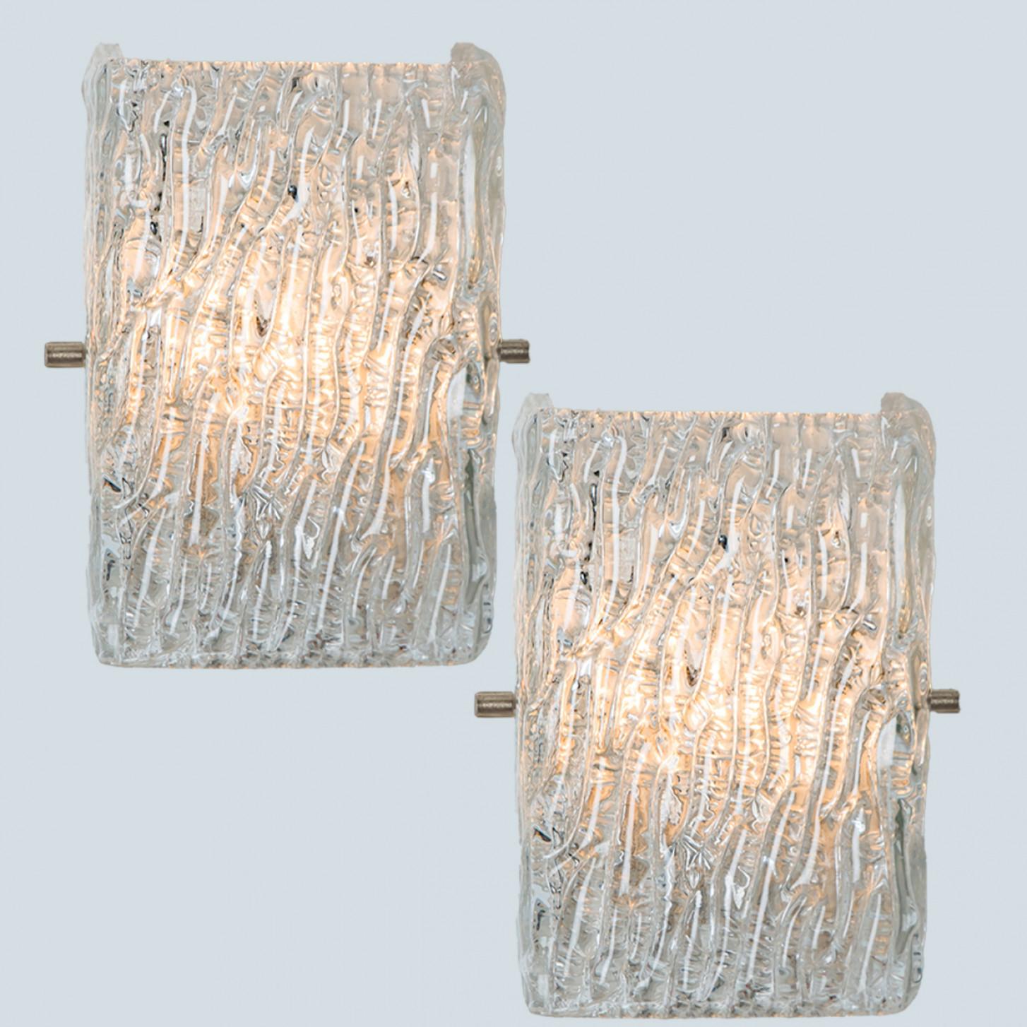 Beautiful high quality light fixture made by Kalmar, Austria. Manufactured in mid century, circa 1970 (at the end of 1960s and beginning of 1970s).

This wall light features lights made of handmade ice glass and white back plate. The sides refract