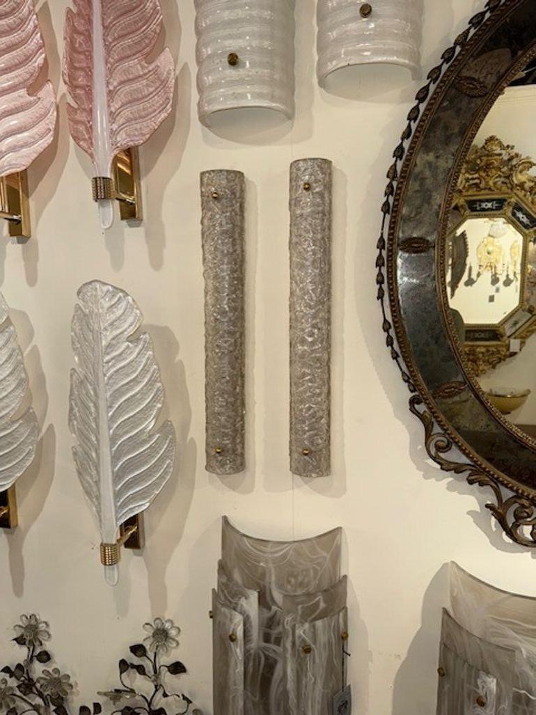 Questo annuncio si riferisce a una coppia di eleganti applique a tubo in vetro di Murano, caratterizzate da un design strutturato per un maggiore interesse visivo. Le applique sono realizzate in vetro argentato e sono ideali per le aree strette.