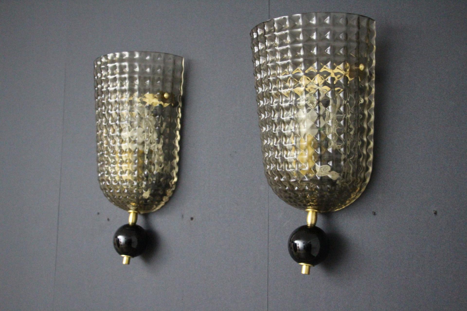 This pair of wall lights was made in Murano. They feature diamond cut in smoked textured Murano glass , looking like a checkers pattern in glass . It is ending with black Murano glass globe finials.Their brass fittings add a touch of preciousness to