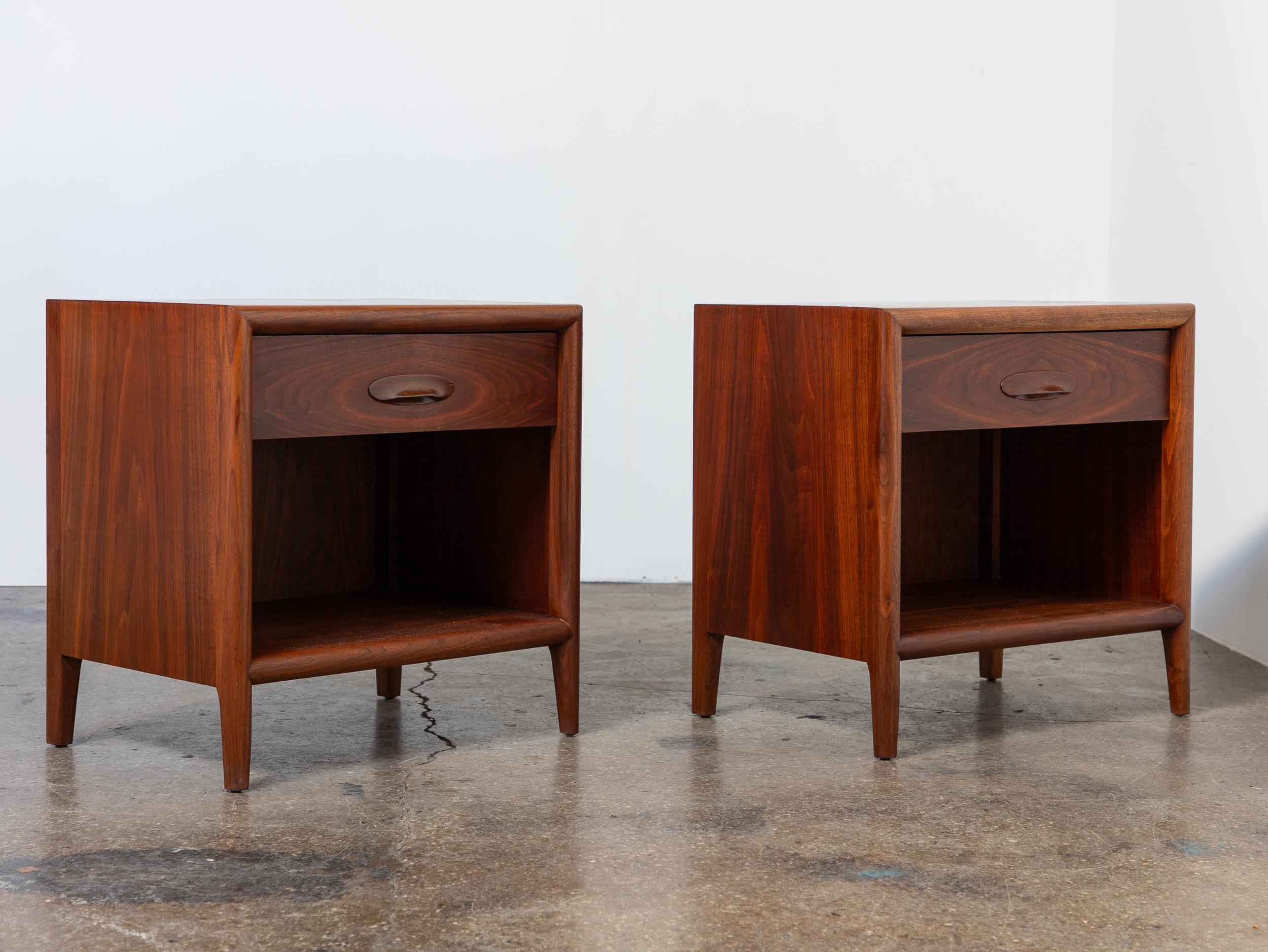 Pair of walnut nightstands by TH Robsjohn-Gibbings for Widdicomb, with sculptural solid wood pulls and softly rounded detailing throughout. The case is defined by clean lines and subtle curves, including a molded front edge that wraps around the top