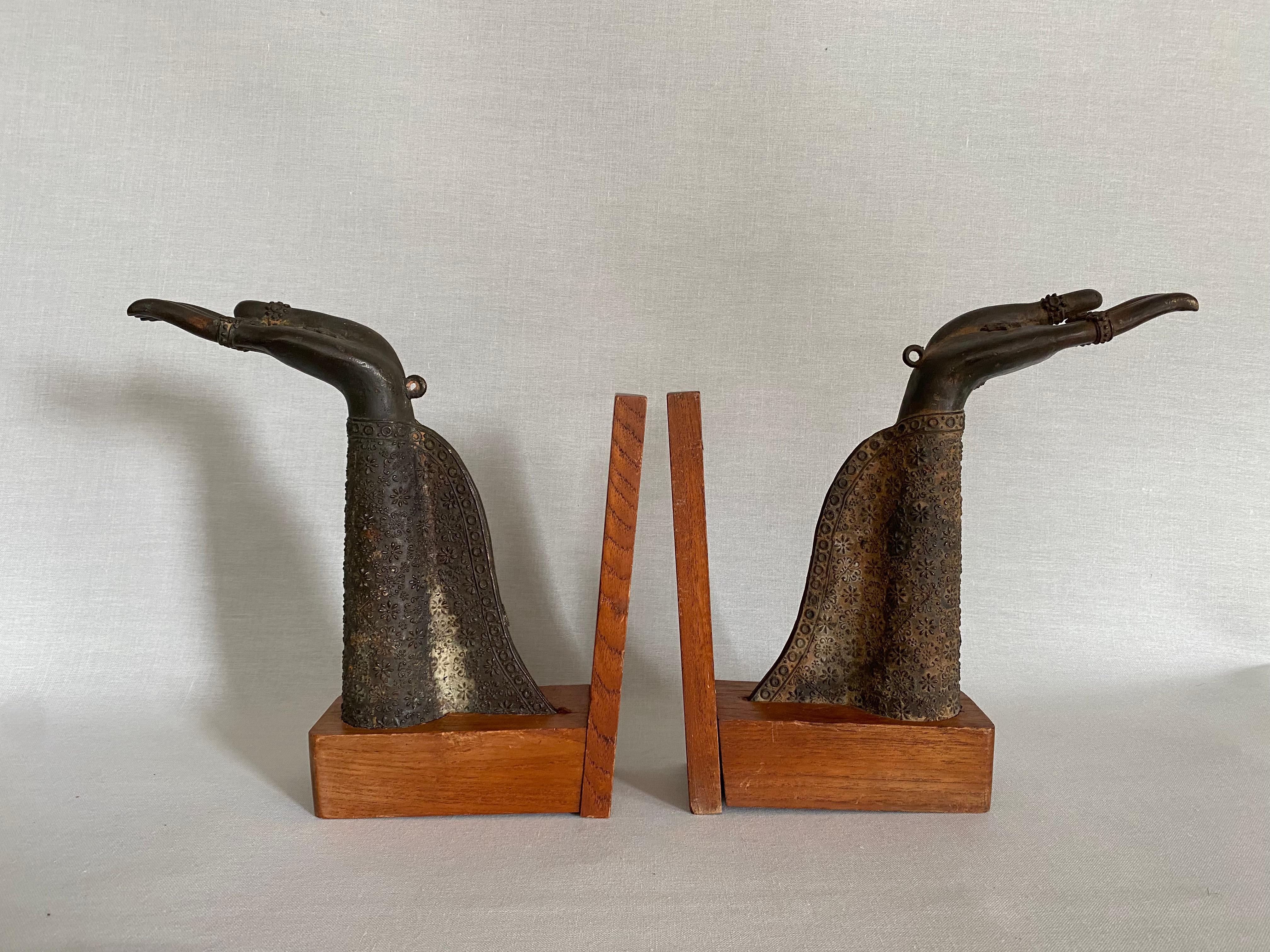 Pair of Thai Bronze Buddha Hands Fragments repurposed as bookends.
The bronze fragments are mounted on simple wooden bases so that they can be used as bookends. The hands and the robe have a beautiful patina and are decorated with many fine