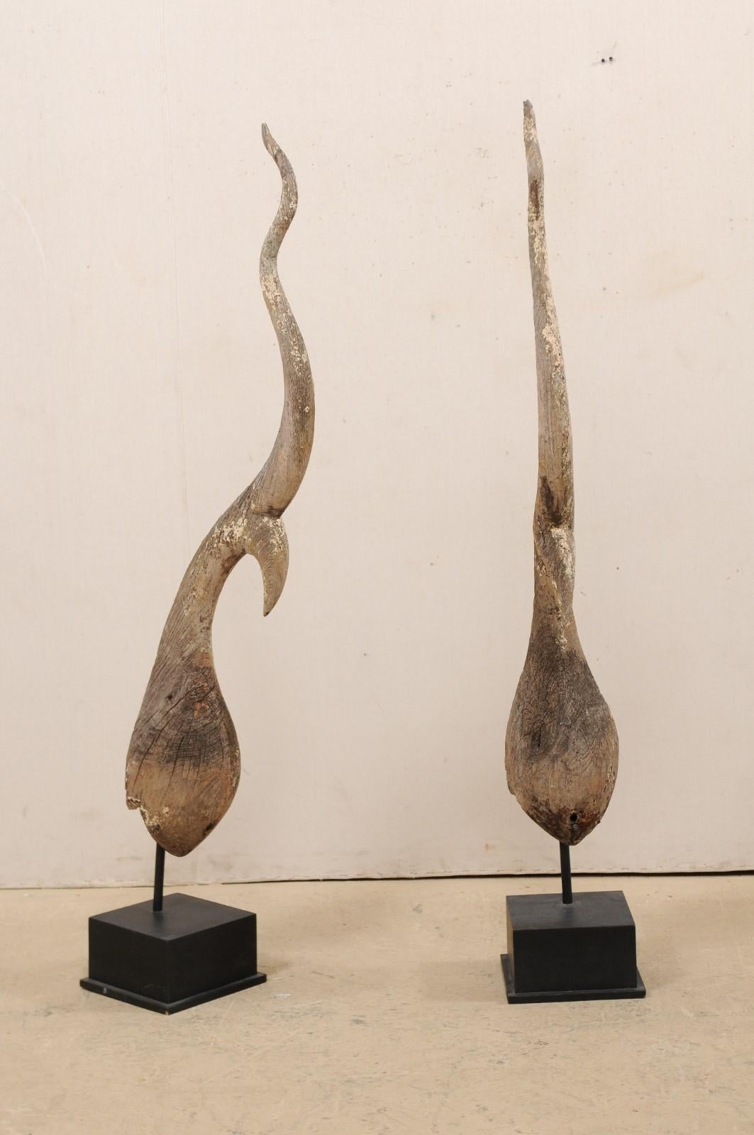 A large-sized pair of antique Chofa temple spires from Thailand, presented on custom wood bases. These elegantly shaped Thai finials, from the late 19th century, are referred to as a 