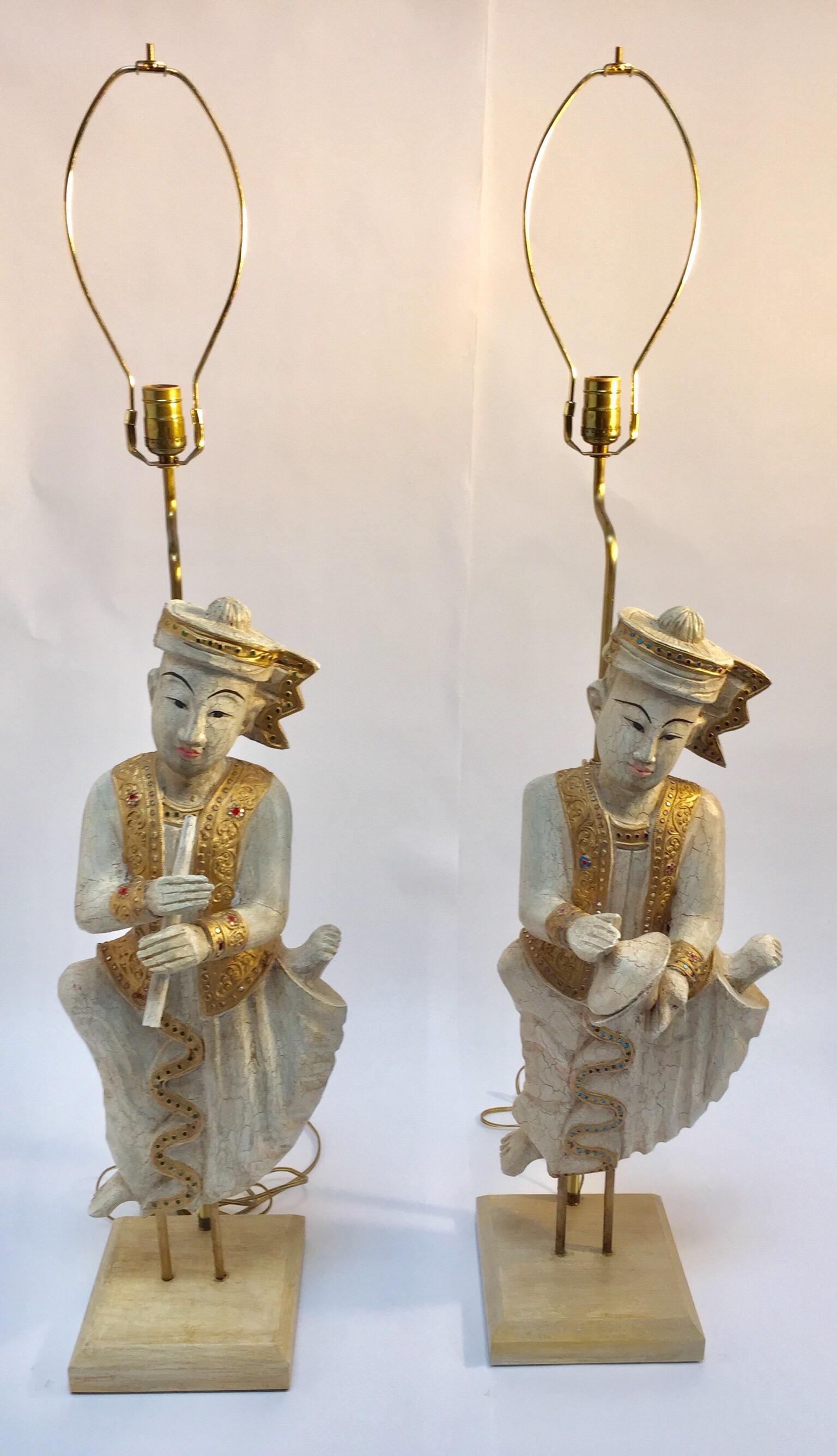 Large pair of Thai figures of Siamese musicians, nicely carved turned into table lamps.
Musicians in seated position, one is holding a flute, the other one symbols, white crackled bleached wood.
Gold gilt adorned with gem red and blue mirror