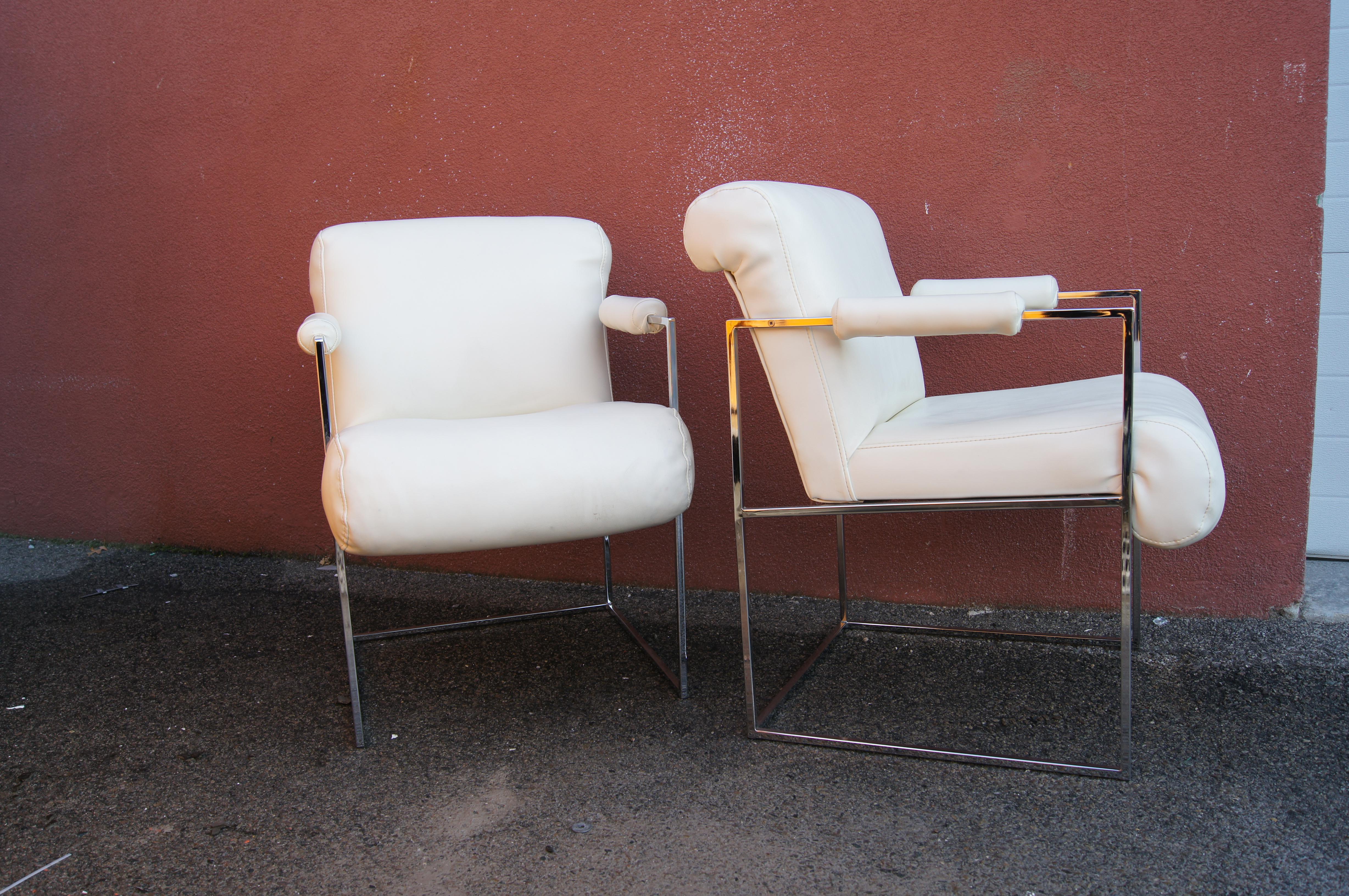 Designed by Milo Baughman as part of the Thin Line Collection for Thayer Coggin, this striking pair of armchairs features thin rectangular frames in chrome with cylindrical padded armrests. The vinyl-upholstered seats slant slightly for added