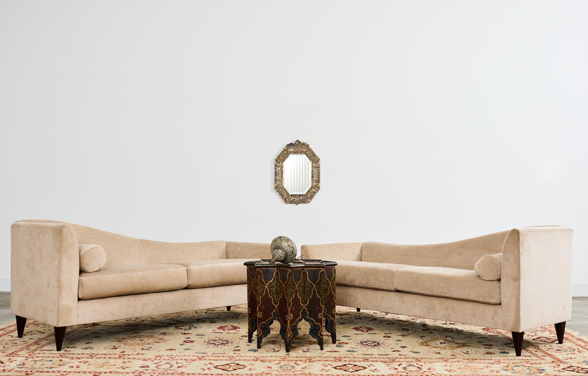 Dramatic pair of left and right side chaise longues or lounges designed by Thomas Pheasant for Baker Furniture. The chaises feature hardwood frames with tightly upholstered fabric seating surfaces. The generous seats have deep-fitted loose seat