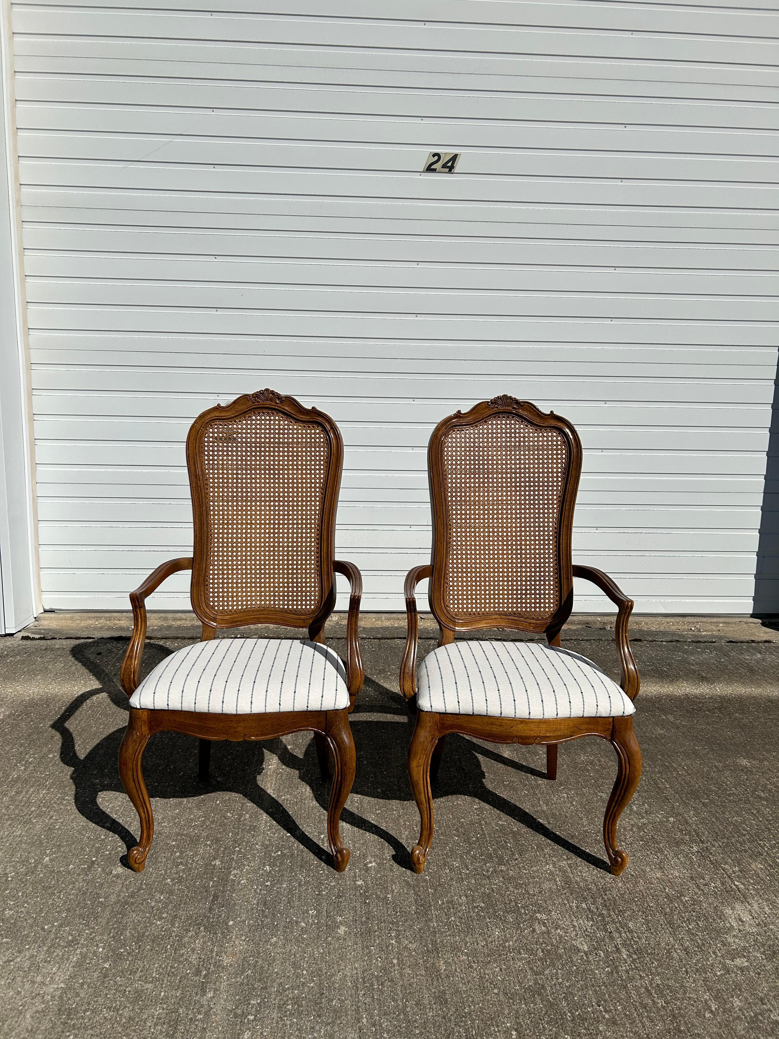 Pair of Thomasville French Provincial Cane Back Dining Arm Chairs. These chairs are in excellent condition, no breaks in the cane and hardly any scratches or gauges in the wood. These chairs have been professionally reupholstered in a beautiful and