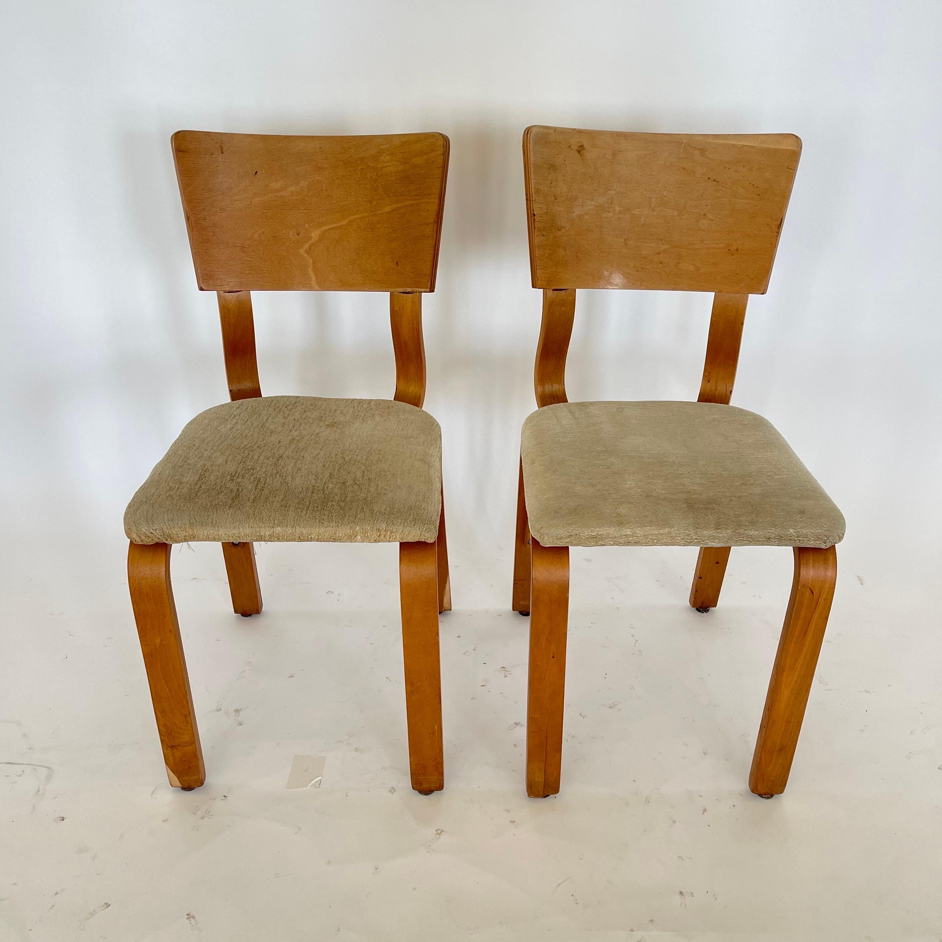 Pair of vintage Thonet 1216-S17-B1 dining or side chairs. Rendered in steam bent oak plywood, with an upholstered seat. This set of chairs is in its original distressed vintage condition, circa 1940s.
