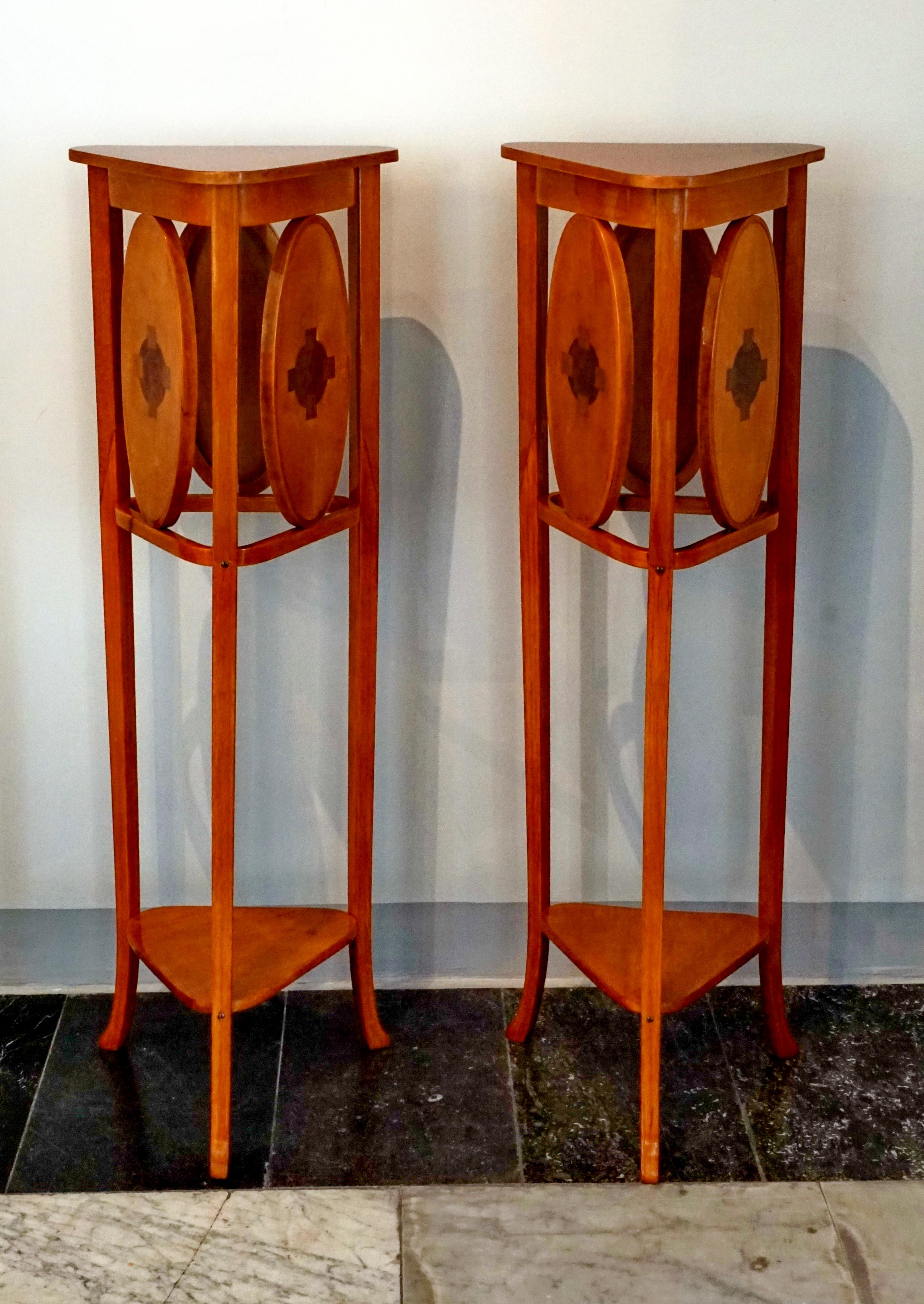 A pair of elegant, simple flower columns, three-legged, shelves in the form of an equilateral triangle with rounded corners; below the shelf between the legs on all three sides oval medallions with inlays Natural beechwood, shellac