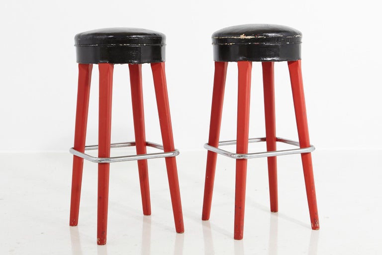 An authentic pair of Thonet stools from the 1930s, marked on the underside with Thonet Logo and certificate.
Red painted wooden base with chrome foot support and black faux leather seats.
The red paint is not original and probably has been added