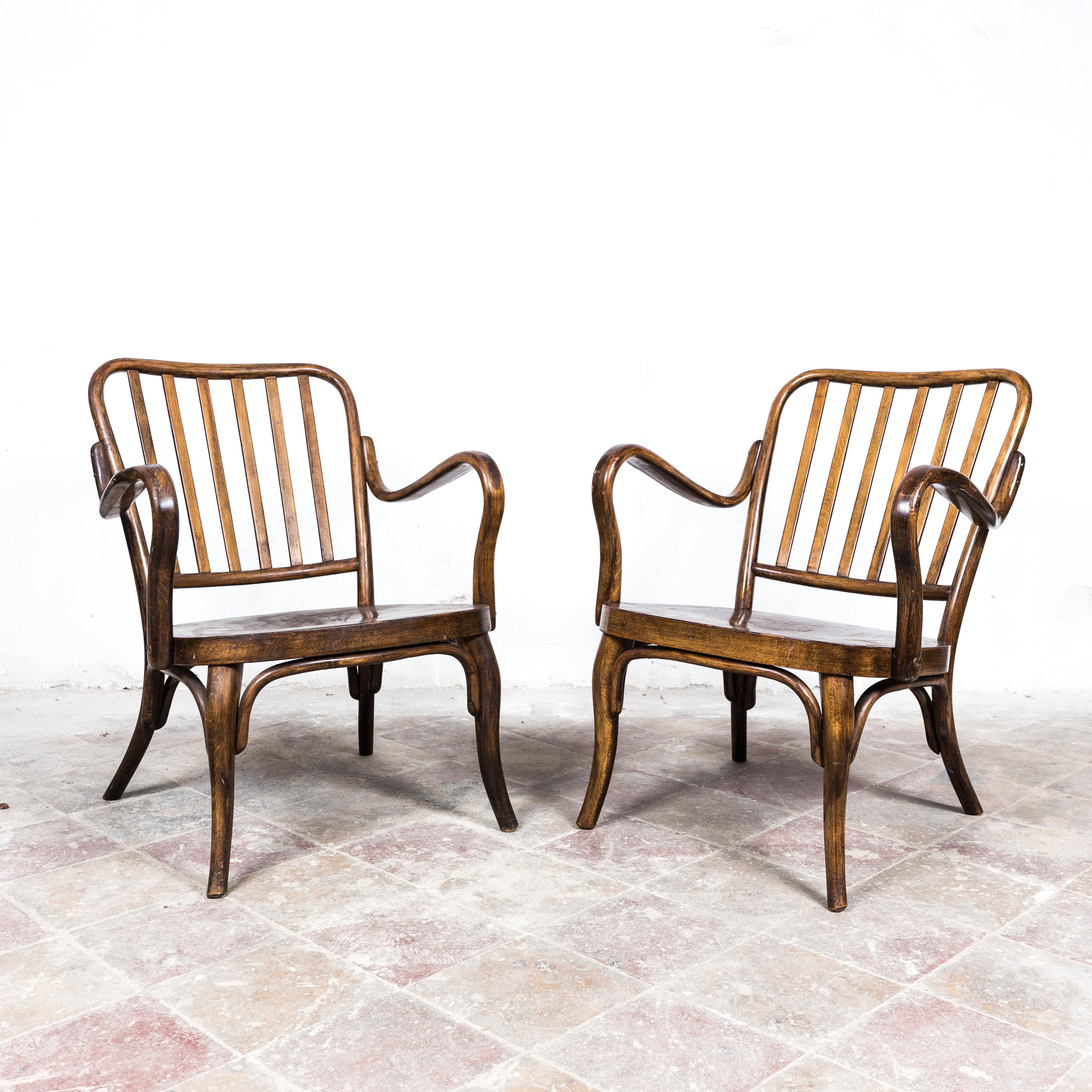 A pair of fireside chairs designed by Josef Frank. Vienna, c. 1930, manufactured by Thonet Mundus, Vienna. Bent beechwood, dark stained and polished plywood seats, in very good original condition, firm and steady. Marked with a Thonet paper label.