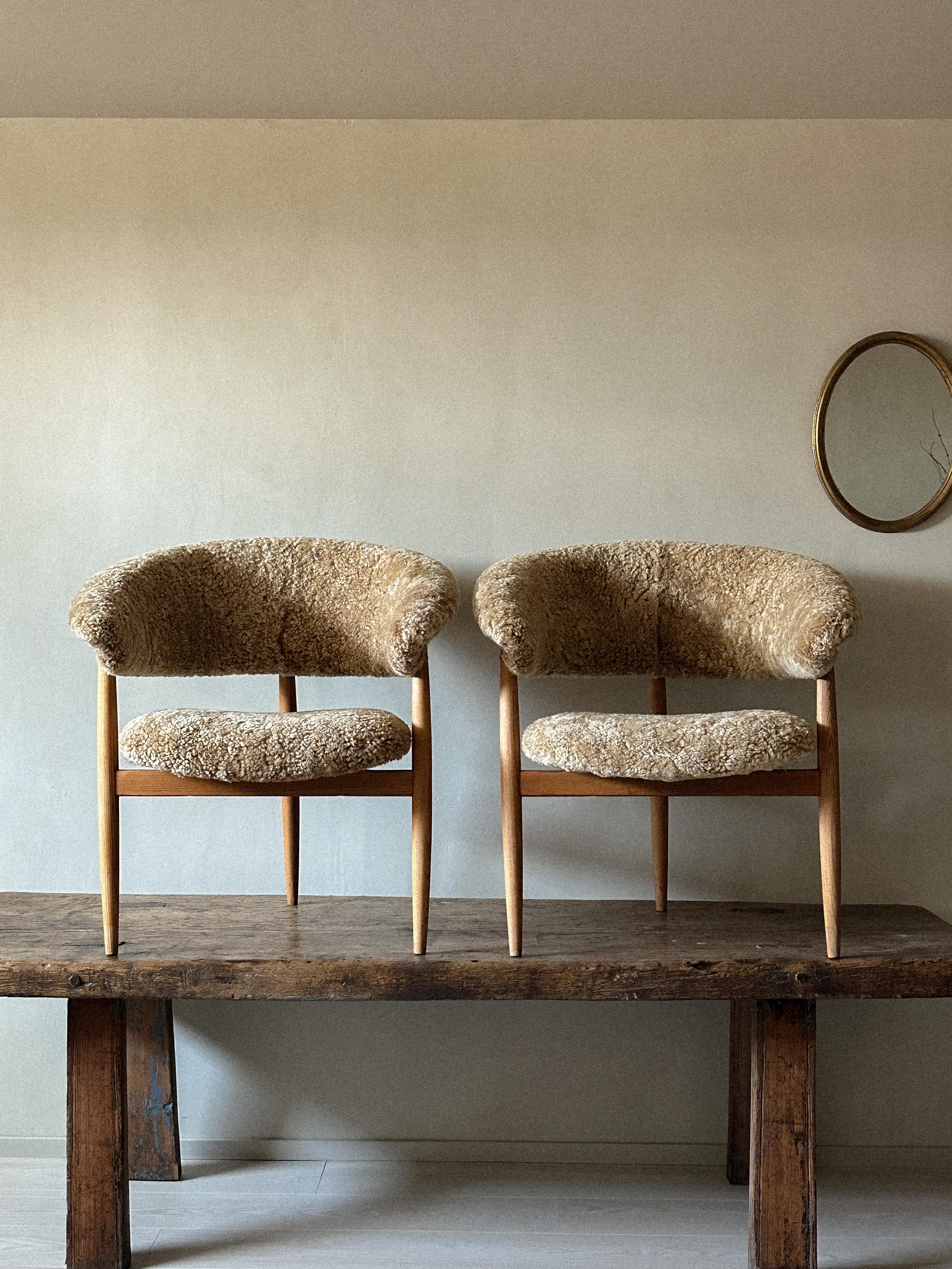 A rare pair of three-legged armchairs by the renowned designer Gerhard Berg, now expertly reupholstered in luxurious premium sheepskin. Originally crafted in the 1950s in Norway, Scandinavia, these chairs are a true testament to timeless elegance