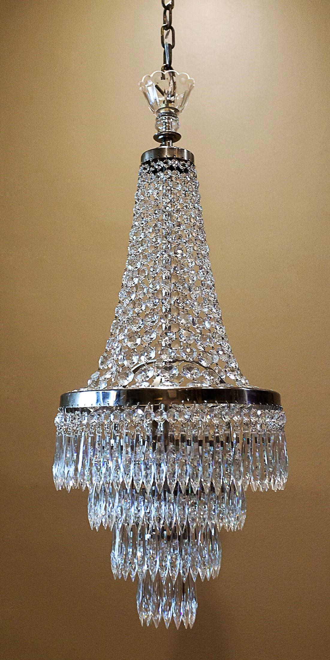 The metal frames and rings on these slender chandeliers are chrome-plated brass, with lead crystal icicle prisms attached. Each socket can take up to a 40-watt candelabra-base bulb. This style of fixture is sometimes called a 