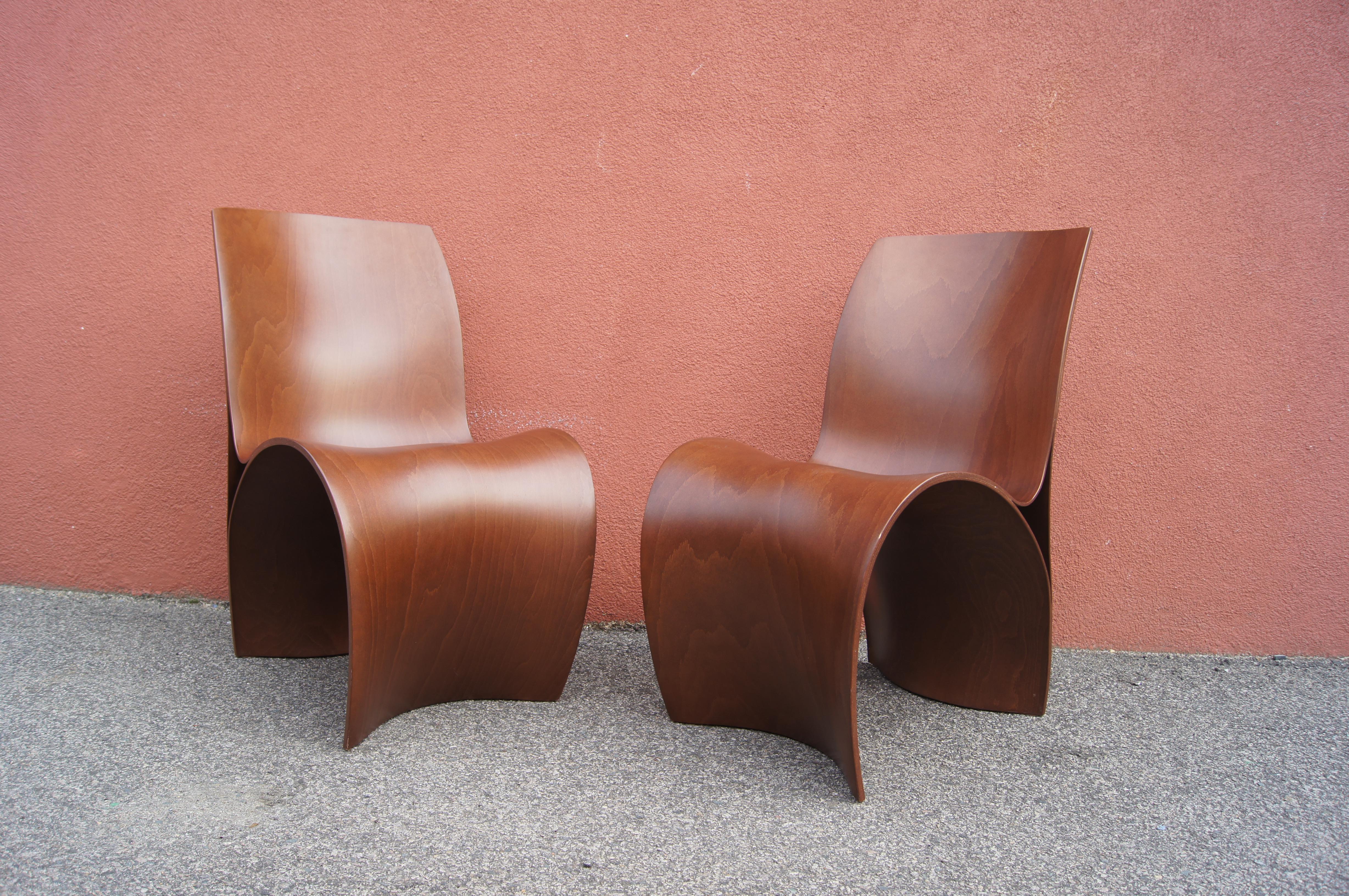 London-based Ron Arad's sinuous three skin chair for Moroso joins multiple layers of lacquered bent beech into a seat that is eye-catching from every angle. This pair are stained a rich auburn brown.