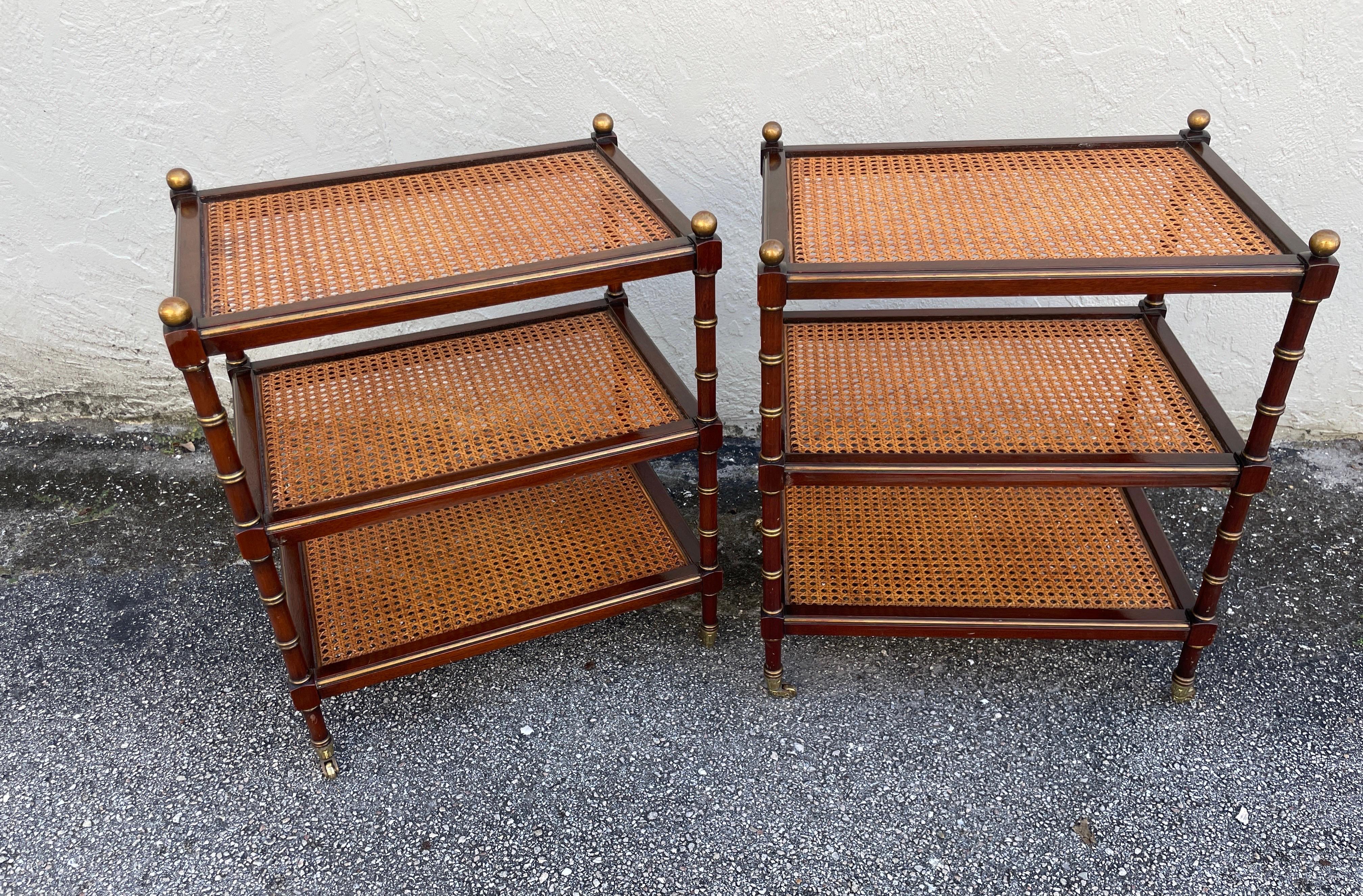 Wonderful pair of three tier side tables with cane shelves and brass casters.
