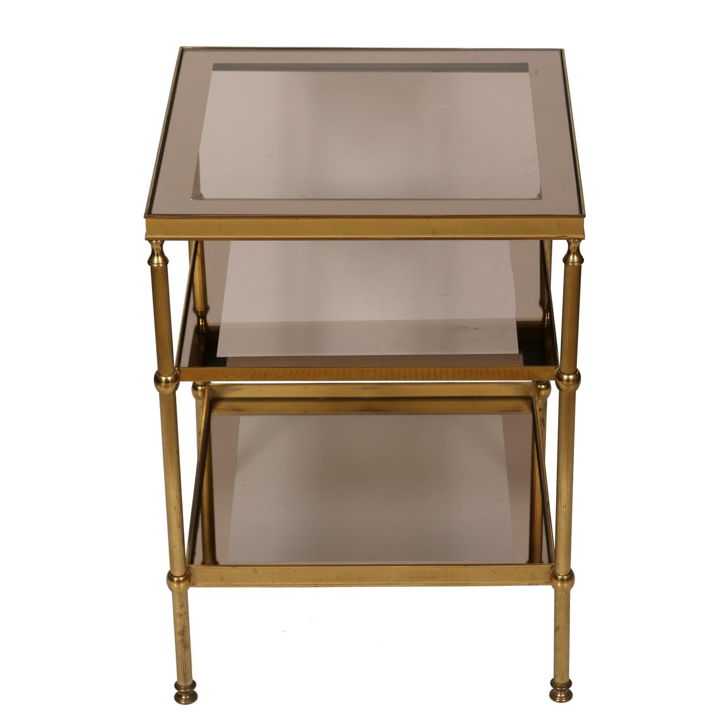 A pair of three tier French brass and bordered smoked glass side tables, circa 1950.