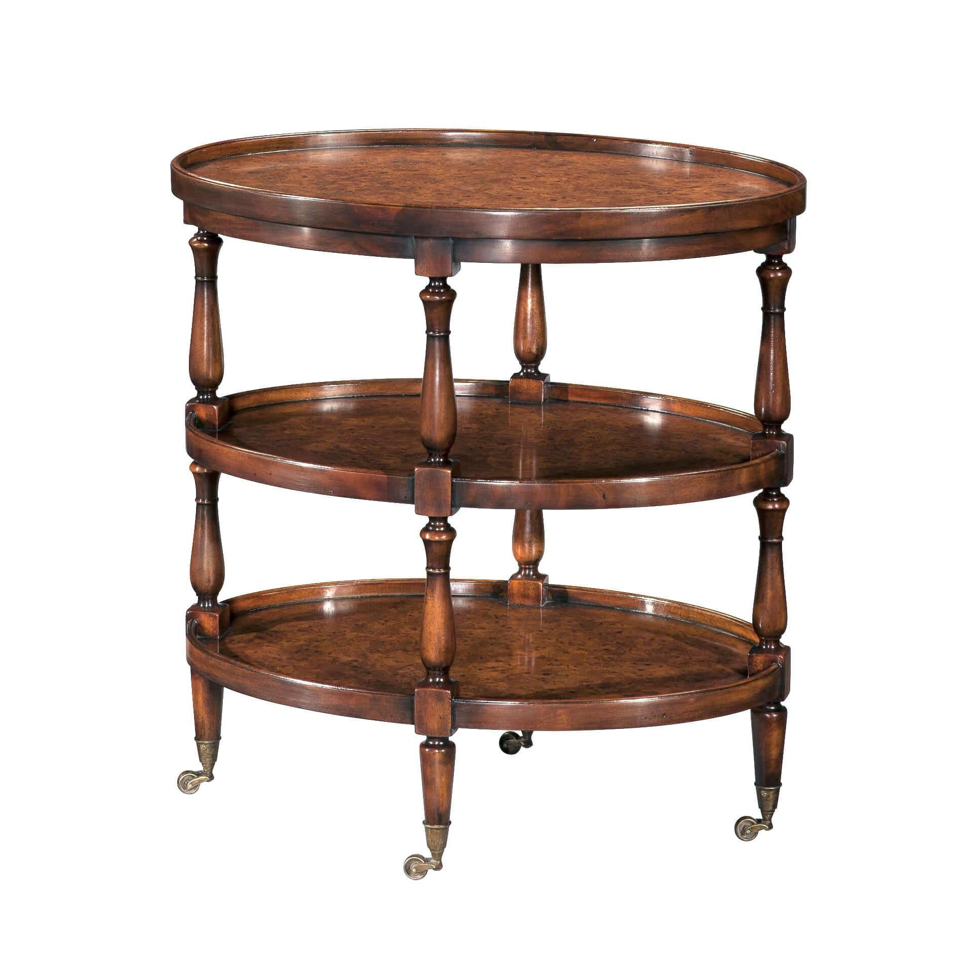 An English burl veneer and solid acacia three-tier end table, the dished oval tray top and two undertakers between baluster turned supports, on turned and tapering legs terminating in brass castors. 

Dimensions: 26“ W x 18.25“ D x 27.25