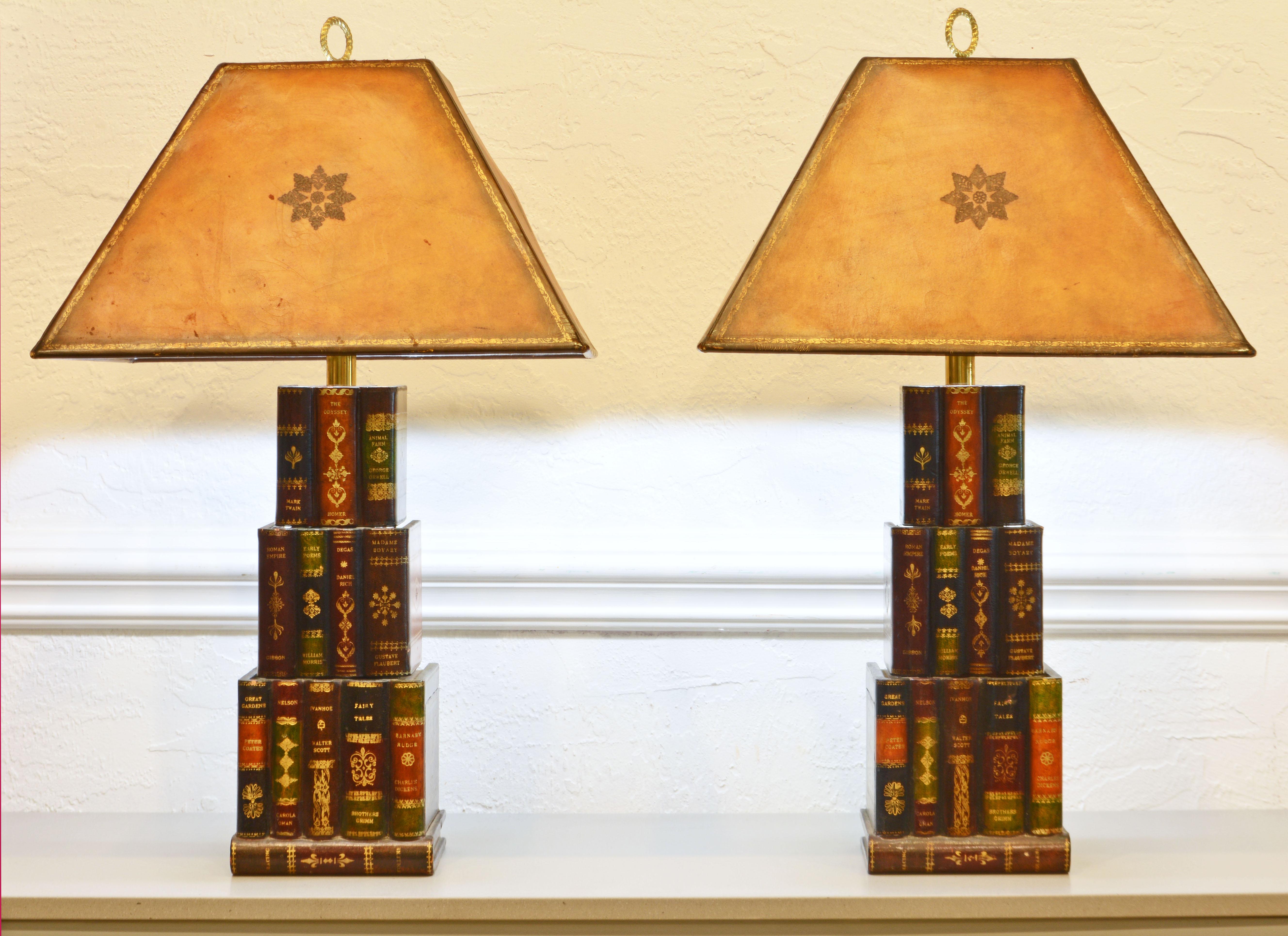 This pair of original Maitland Smith three level book lamps are retaining their original gilt tooled leather shades. The structure of the lamps are carved in wood and covered in gilt decorated leather simulating stacks of real books. Every book has