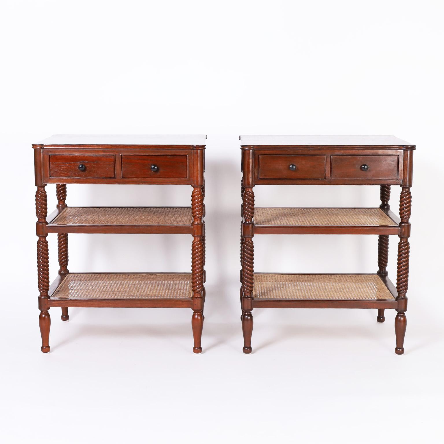 Pair of British colonial style stands crafted in mahogany with two drawers in the top case, two lower caned tiers with elegant turned supports and legs.