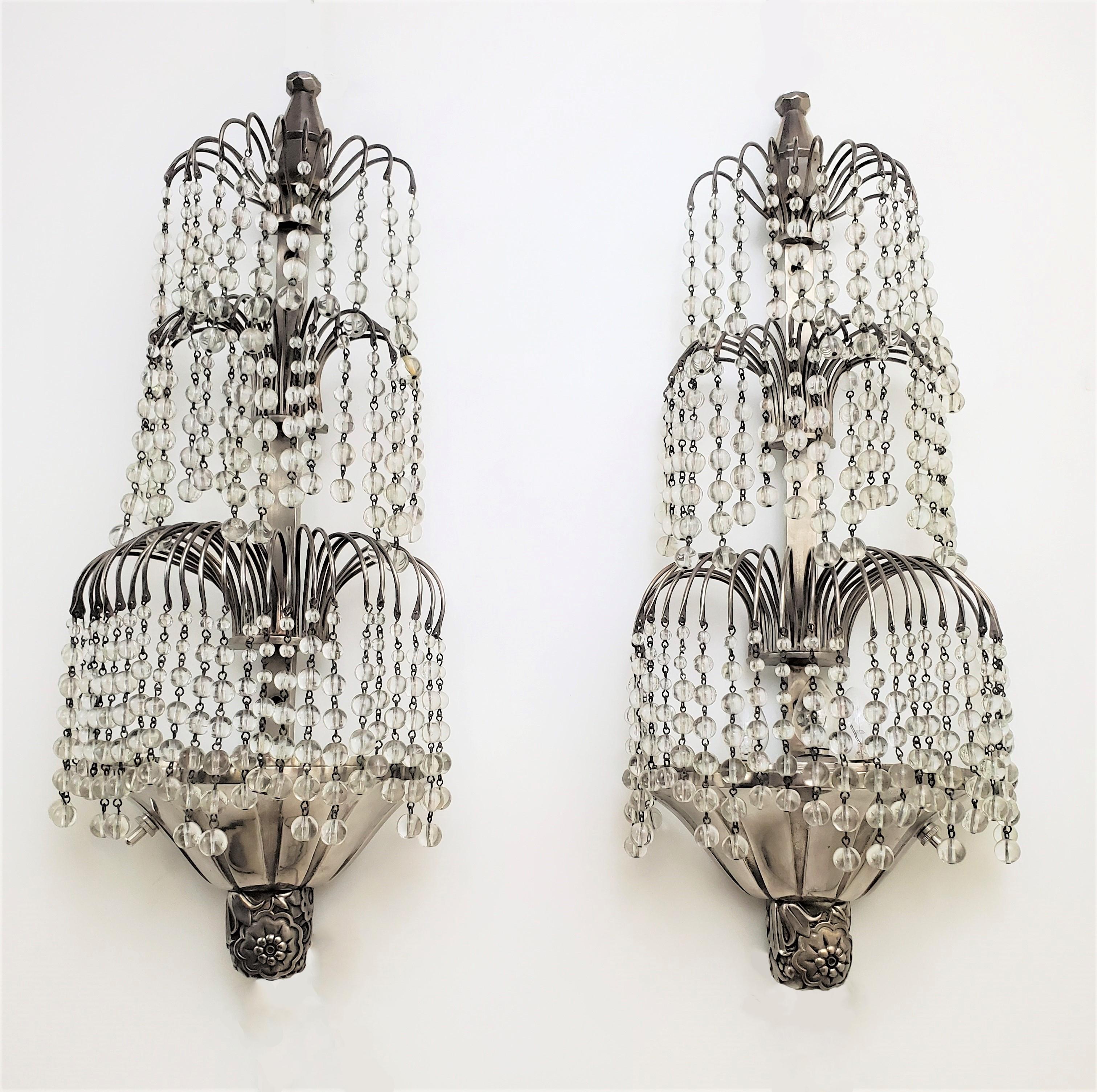 A pair of elegant French Art Deco tiered waterfall sconces attributed to Louis Süe and André Mare. Delicate and dazzling crystal beads of glass cascade down on three levels from a nickeled bronze armature ending with fluted cap and a stylized