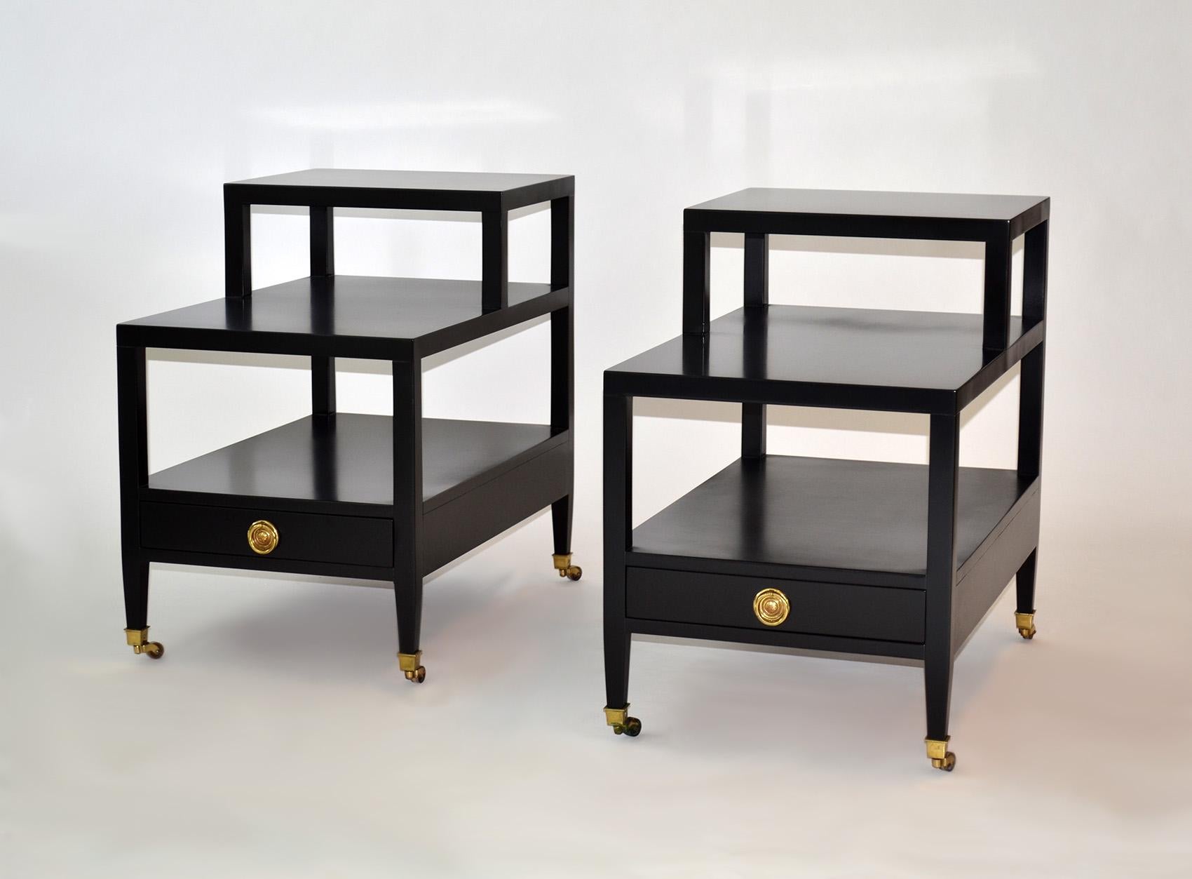 Pair of tiered end or side tables single drawer by Baker Furniture Mid-Century.
Rare pair of end or side tiered tables single drawer black by Baker Mid-Century.
Black lacquered wood with brass pulls, sabots and wheels (one wheel is stuck).
