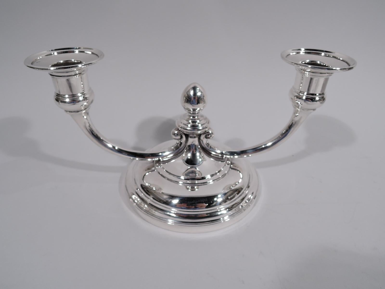 Pair of Art Deco sterling silver 2-light candelabra. Made by Tiffany & Co. in New York. Each: Large round and domed base with raised center terminating in acorn finial. Two low-slung c-scroll branches, each terminating in single Campana vase socket