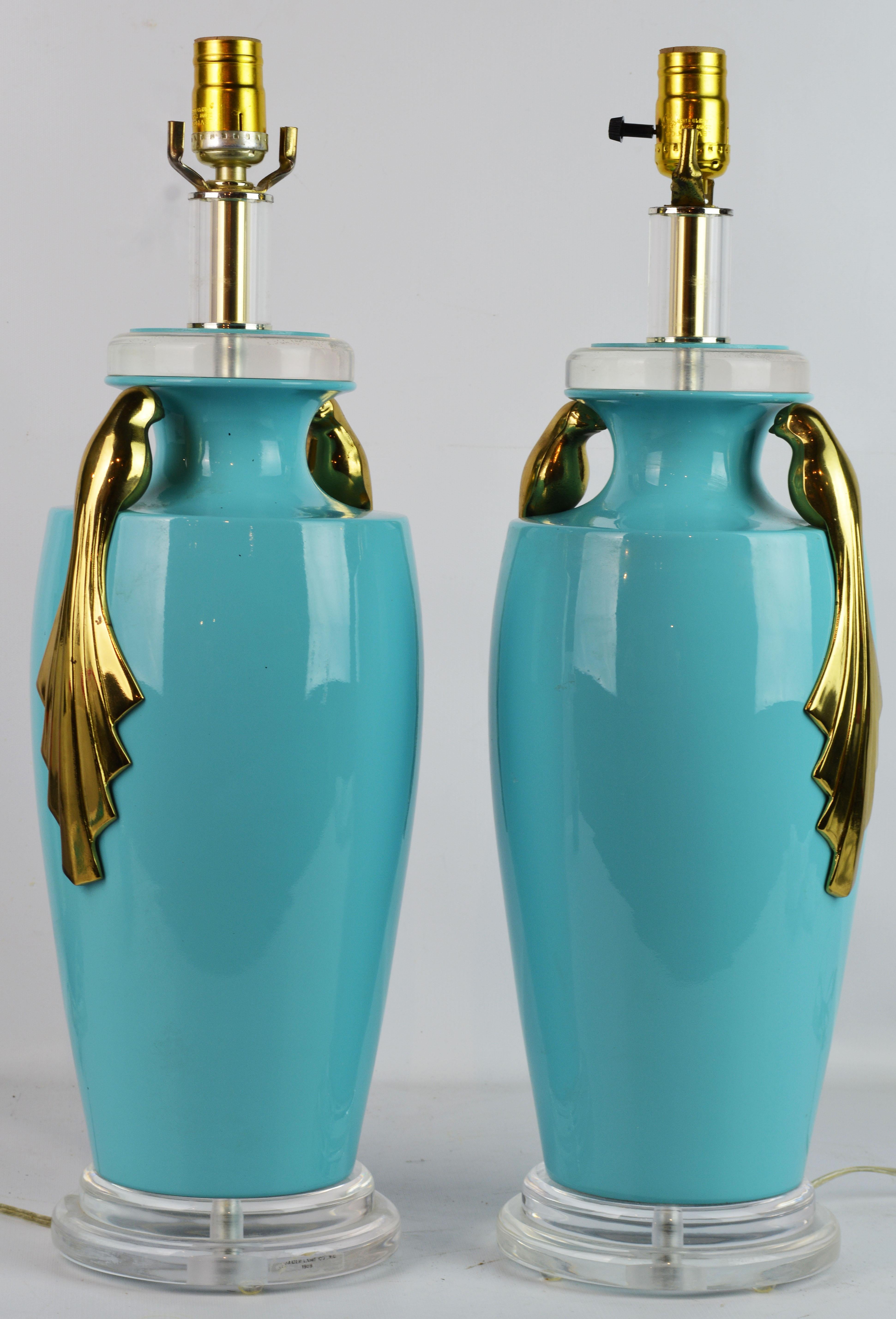 These Art Deco style table lamps by Bauer Lamp Company features Tiffany blue ceramic glazed bodies in the shape of Classic urns mounted with double stylized solid brass paradise birds. The lamps have Lucite bases and tops making the overall