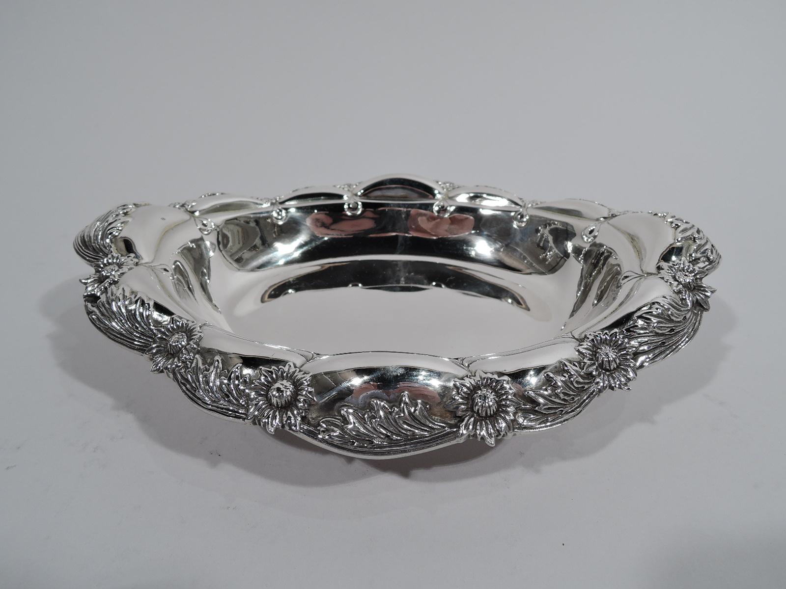 Pair of chrysanthemum sterling silver serving bowls. Made by Tiffany & Co. in New York. Each: Oval well and turned-down petal rim in alternating leaf and flower head pattern. Short foot with applied scrolls. Restrained and elegant pieces in the