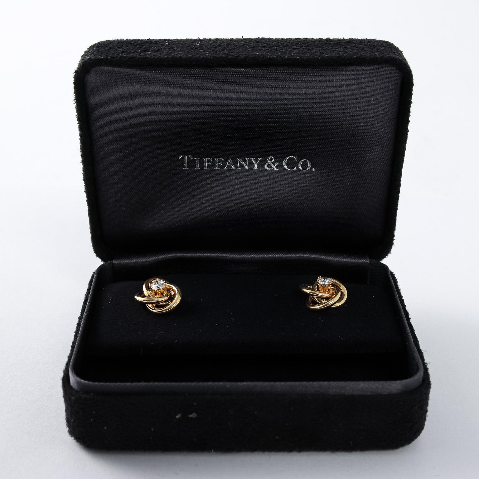 Circa 1990s pair of Tiffany & Co. Designer 18k Yellow Gold love knot earring studs. The earrings feature two high quality brilliant cut diamonds that are E-F color and VVS clarity. Each measure 3.5 mm that are 0.17 carats each. Tiffany & Company