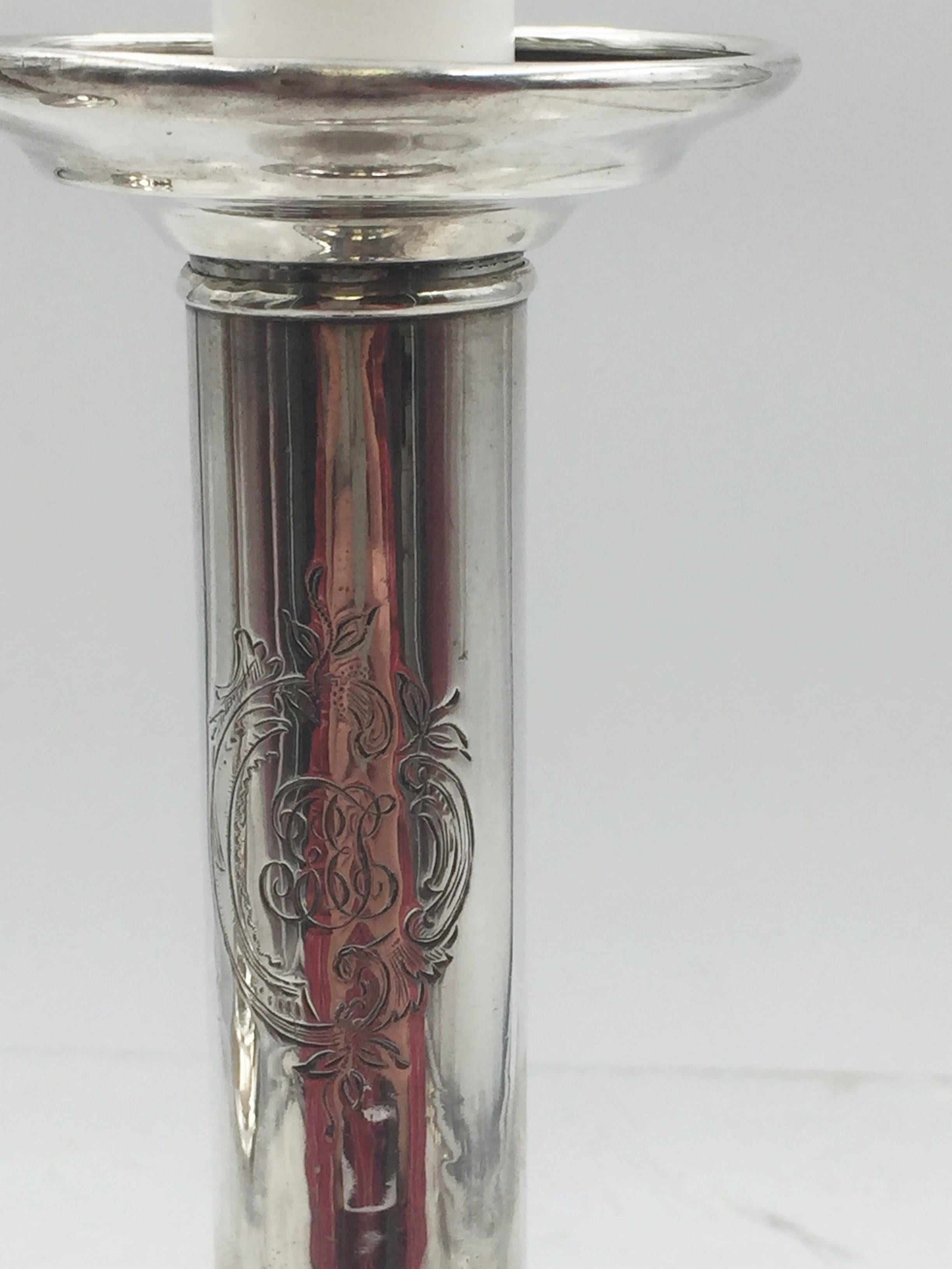 Pair of Tiffany & Co. sterling silver weighted candlesticks in pattern number 15562 from 1903 with cartouches engraved with floral motifs and a monogram, measuring 5 1/2” in height. The diameter of the base measures 3 1/8”. Bearing hallmarks as