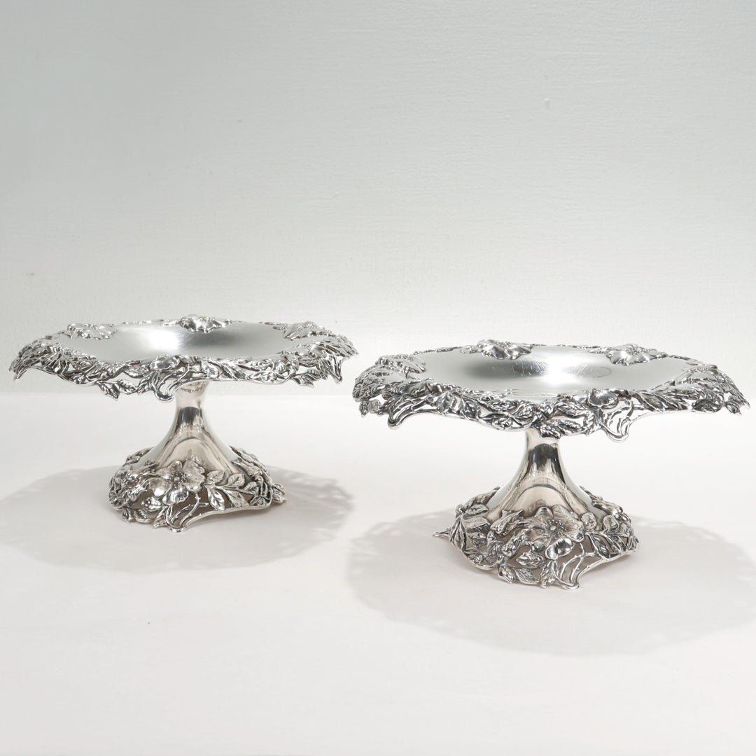 A fine pair of compotes or tazzas.

By Tiffany & Co.

In sterling silver.

With borders decorated with cast wild roses & leafwork and openwork branches & stems that comprise the rims and feet.

Each with a scrolling monogram to its