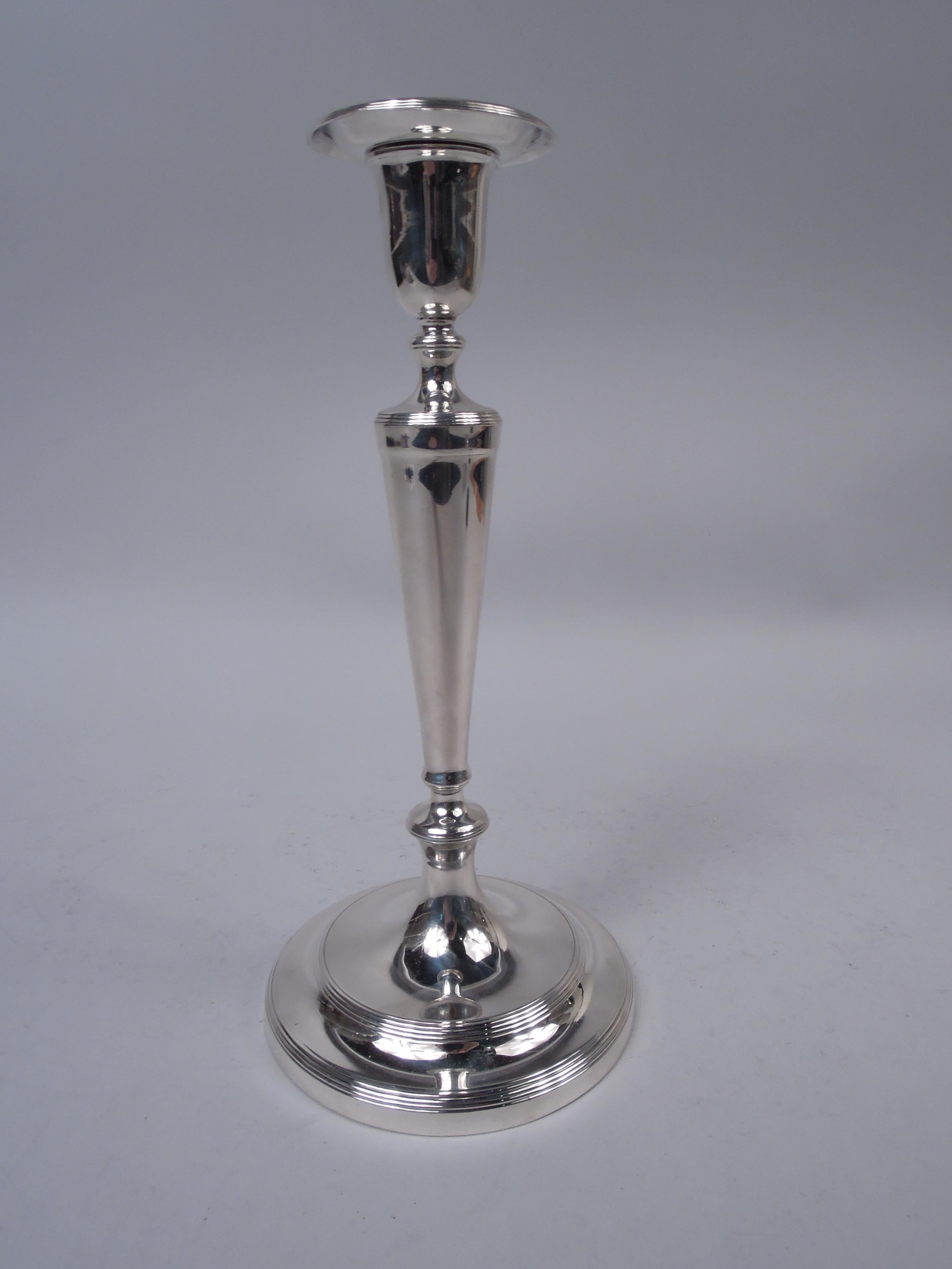 Edwardian Classical sterling silver candlesticks. Made by Tiffany & Co. in New York, ca 1908. Urn socket with detachable bobeche, tapering columnar shaft, knops, and stepped foot. Spare form embellished with reeding. An elegant pair that works on