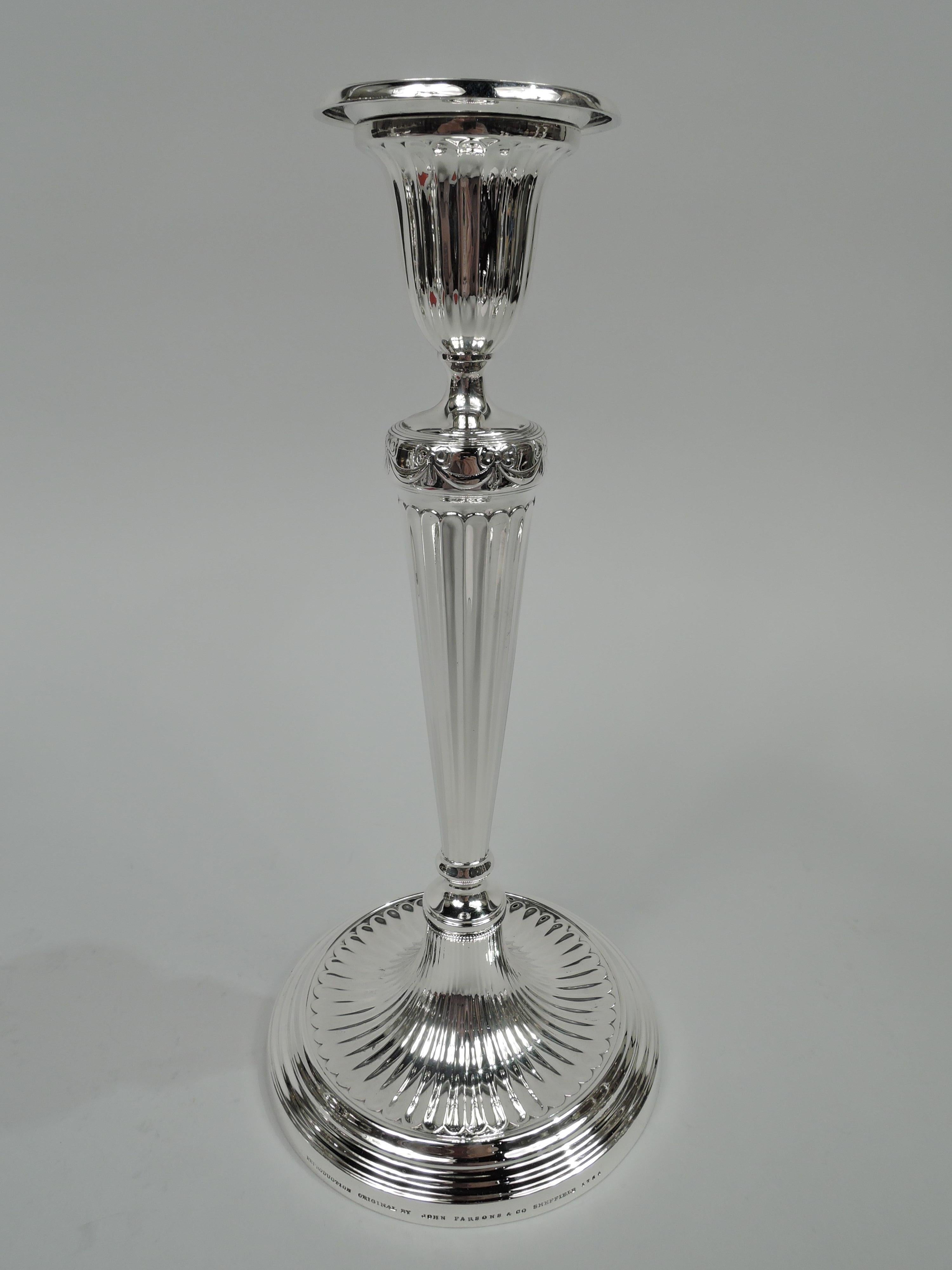 Pair of English neoclassical sterling silver candlesticks. Made by Tiffany & Co. in New York, ca 1916. Each: Tapering column on dome flowing into stepped and concave base. Tapering socket with detachable bobeche. Ribboned swags. Fine fluting that
