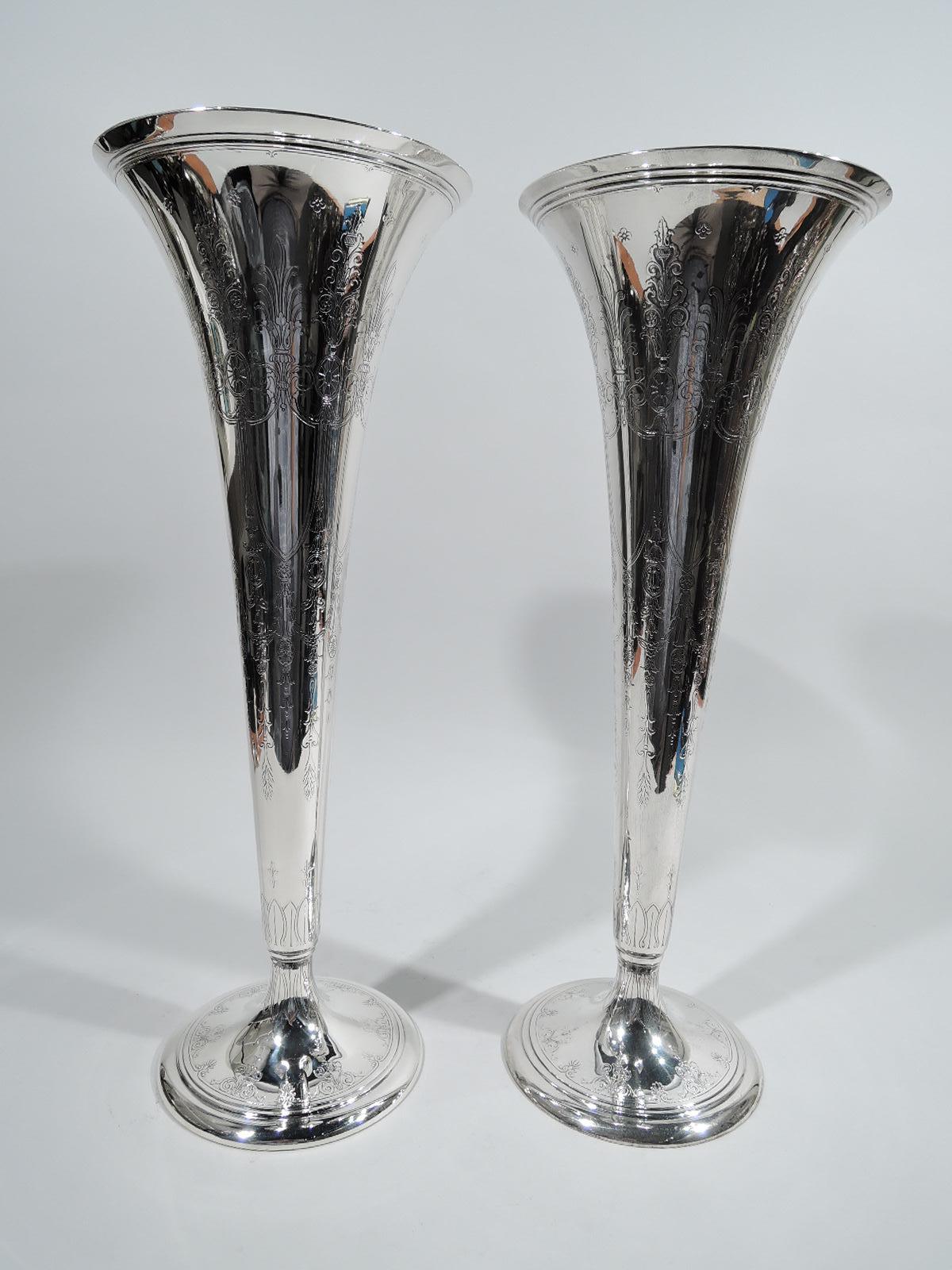 Pair of Edwardian Regency sterling silver trumpet vases. Made by Tiffany & Co. in New York, ca 1913. Each: Tapering sides and stepped raised foot. Acid-etched repeating pattern with swags and paterae and armorial shield frames (all vacant). Stylized