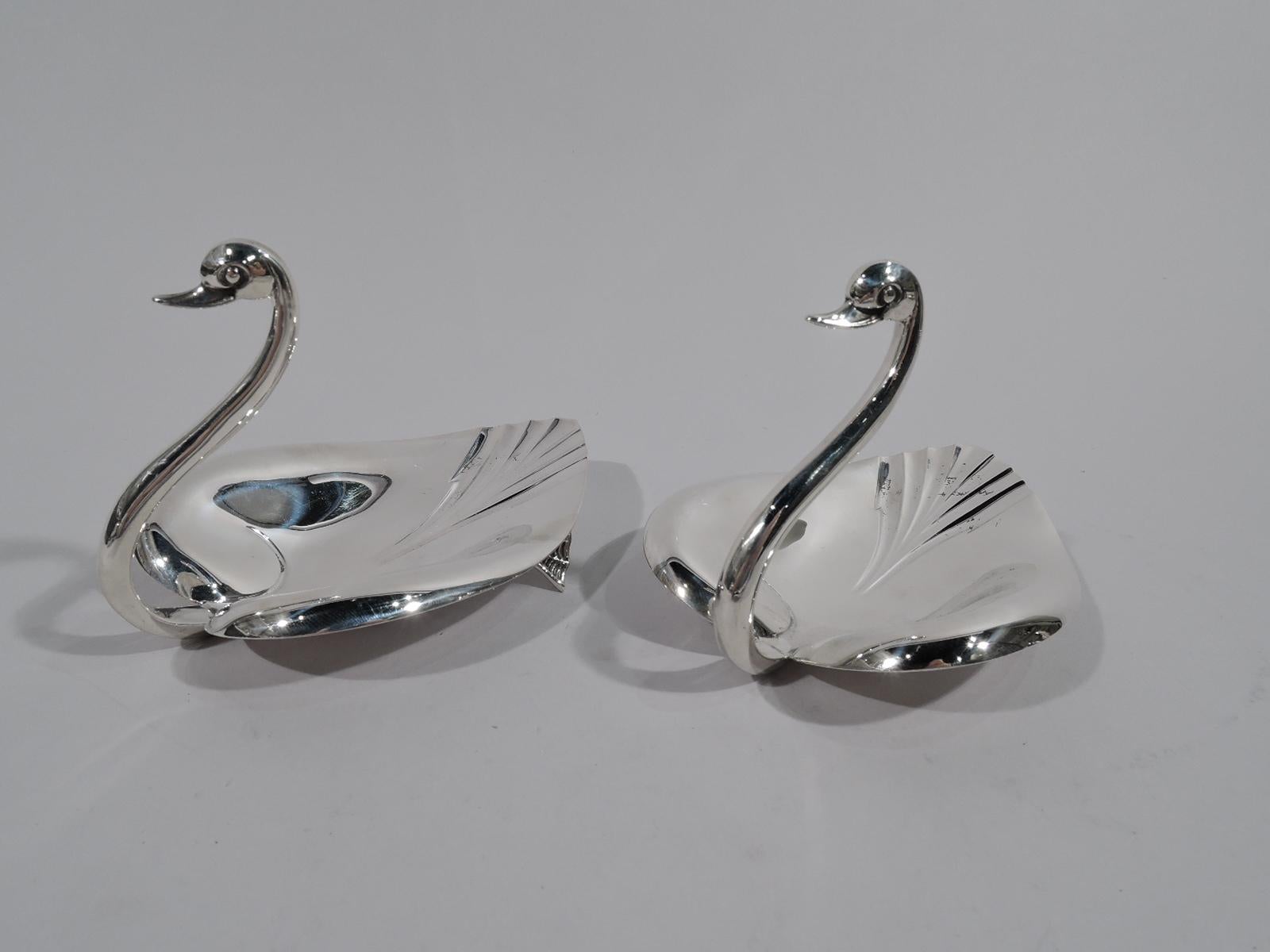 Pair of Mid-Century Modern sterling silver bowls. Made by Tiffany & Co. in New York. Each: Semi-abstract swan with lifted heart-shaped bowl with chased volute scrolls and fluted tale. S-scroll neck terminating in head with bead eyes and bill. Rests