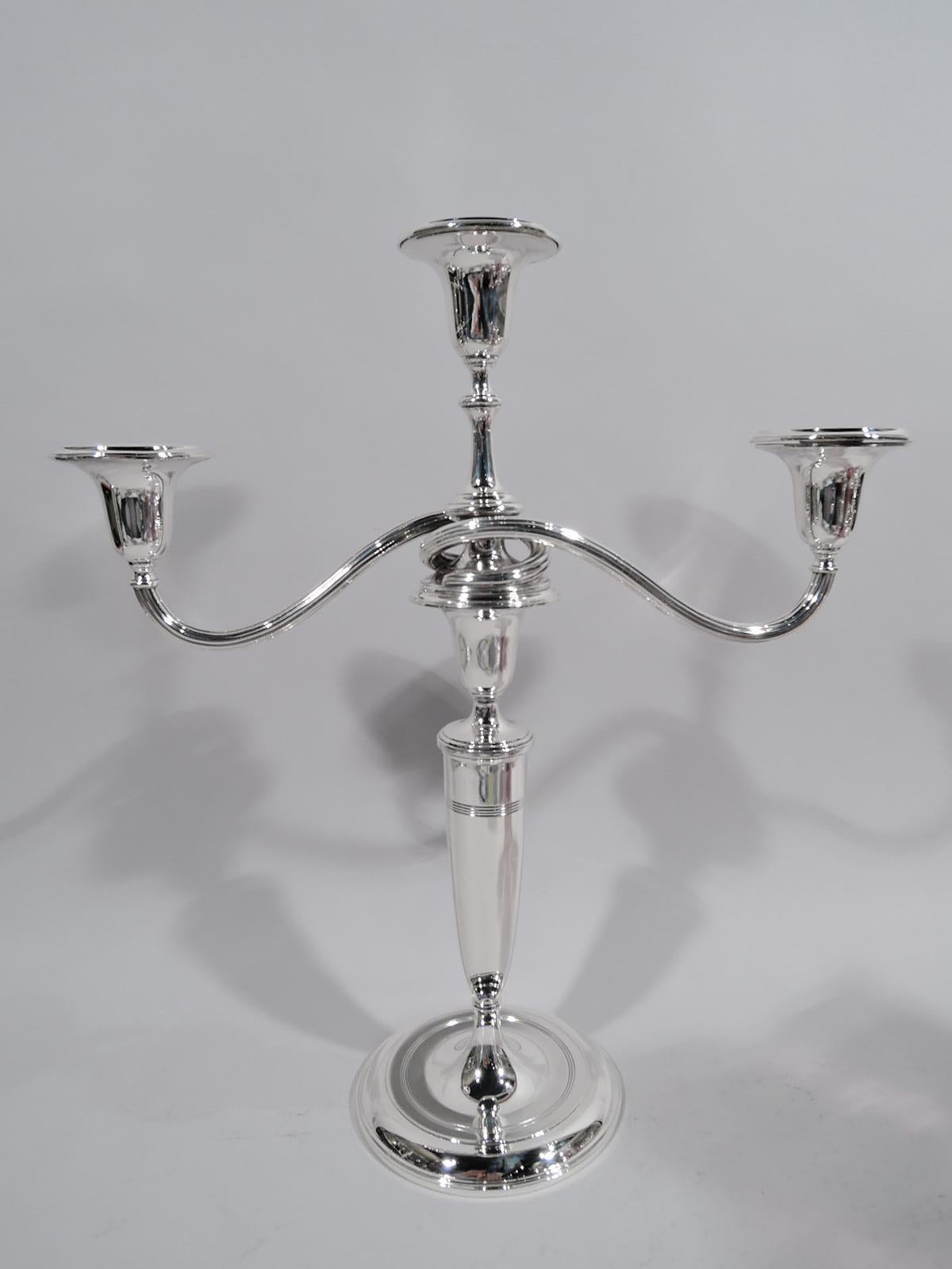Pair of Modern classical elegant sterling silver 3-light candelabra. Made by Tiffany & Co. in New York. Each: Urn socket on tapering shaft on raised foot. Central urn socket on tall spool shaft with wraparound reeded arms, each terminating in single
