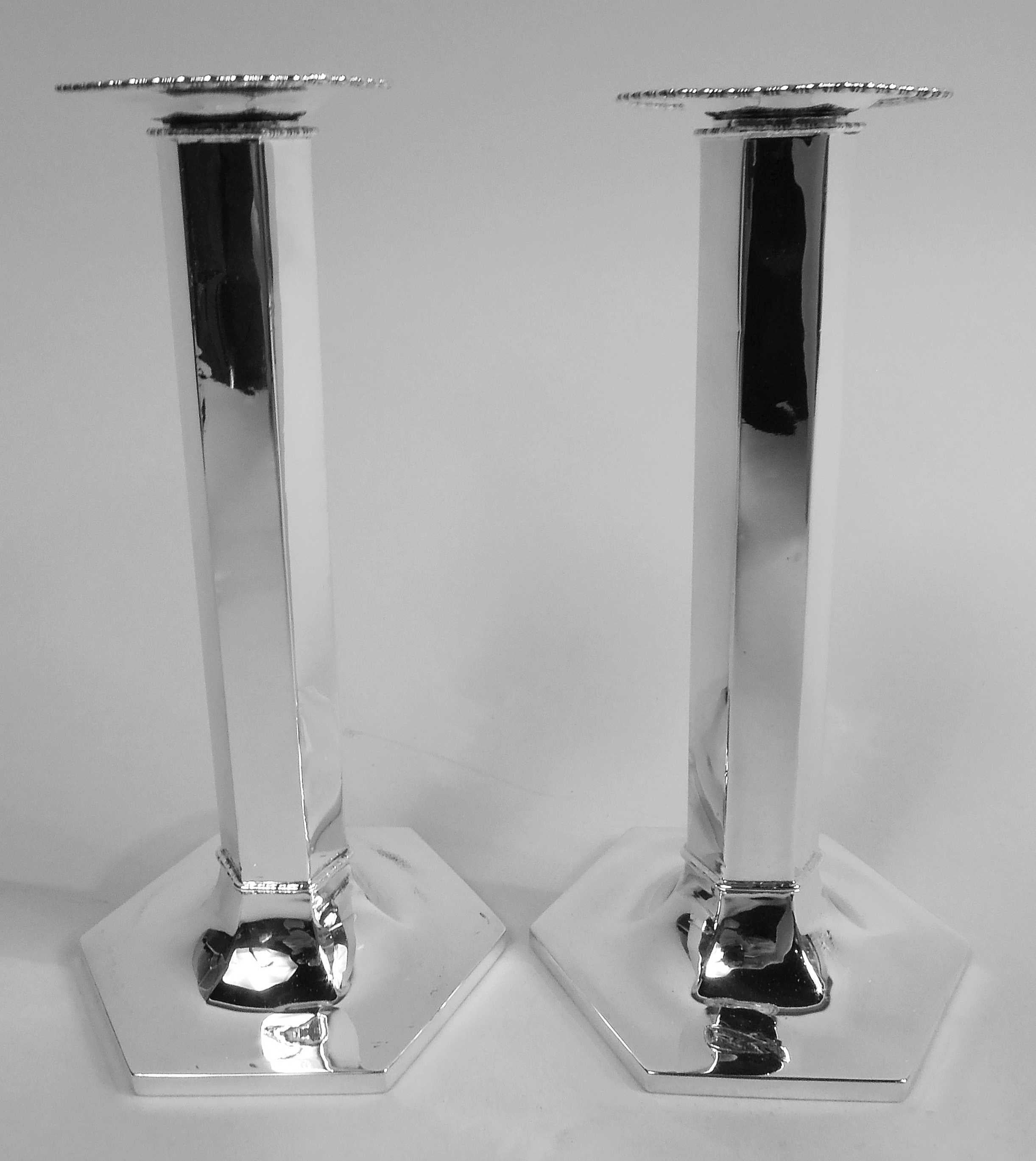 Pair of American Modern Classical sterling silver candlesticks, ca 1925. Each: Faceted column applied with bead-and-reel borders at top and bottom; raised hexagonal foot and detachable bobeche applied with same. Marks include retailer’s stamp (“Made