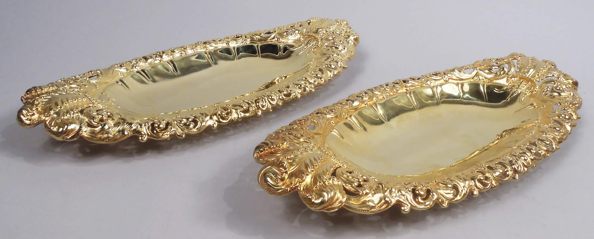 Pair of Victorian sterling silver bread trays. Made by Tiffany & Co. in New York. Ovoid well with fluid egg-and-dart border. Pierced and chased rim with dynamic leafing scrollwork; Prince of Wales feathers at ends. Sumptuous, nicely toned gilding.