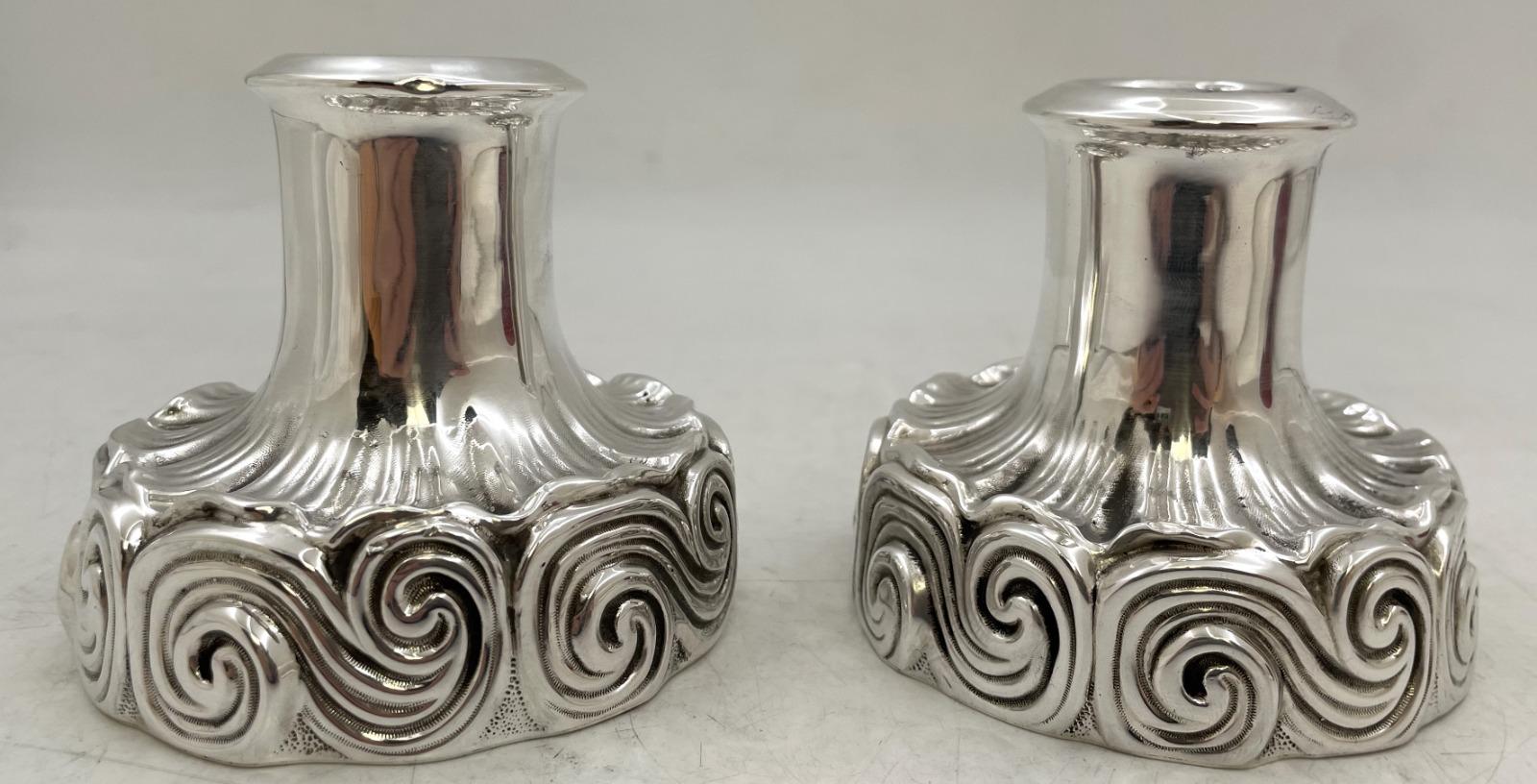 Pareja de candelabros de plata de ley de Tiffany & Co., diseñados por Louis Comfort Tiffany, con motivos curvilíneos de estilo ondulado. Miden 3 1/3'' de altura por 3 3/4'' de diámetro en la base, pesan 10 onzas troy y llevan los sellos que se
