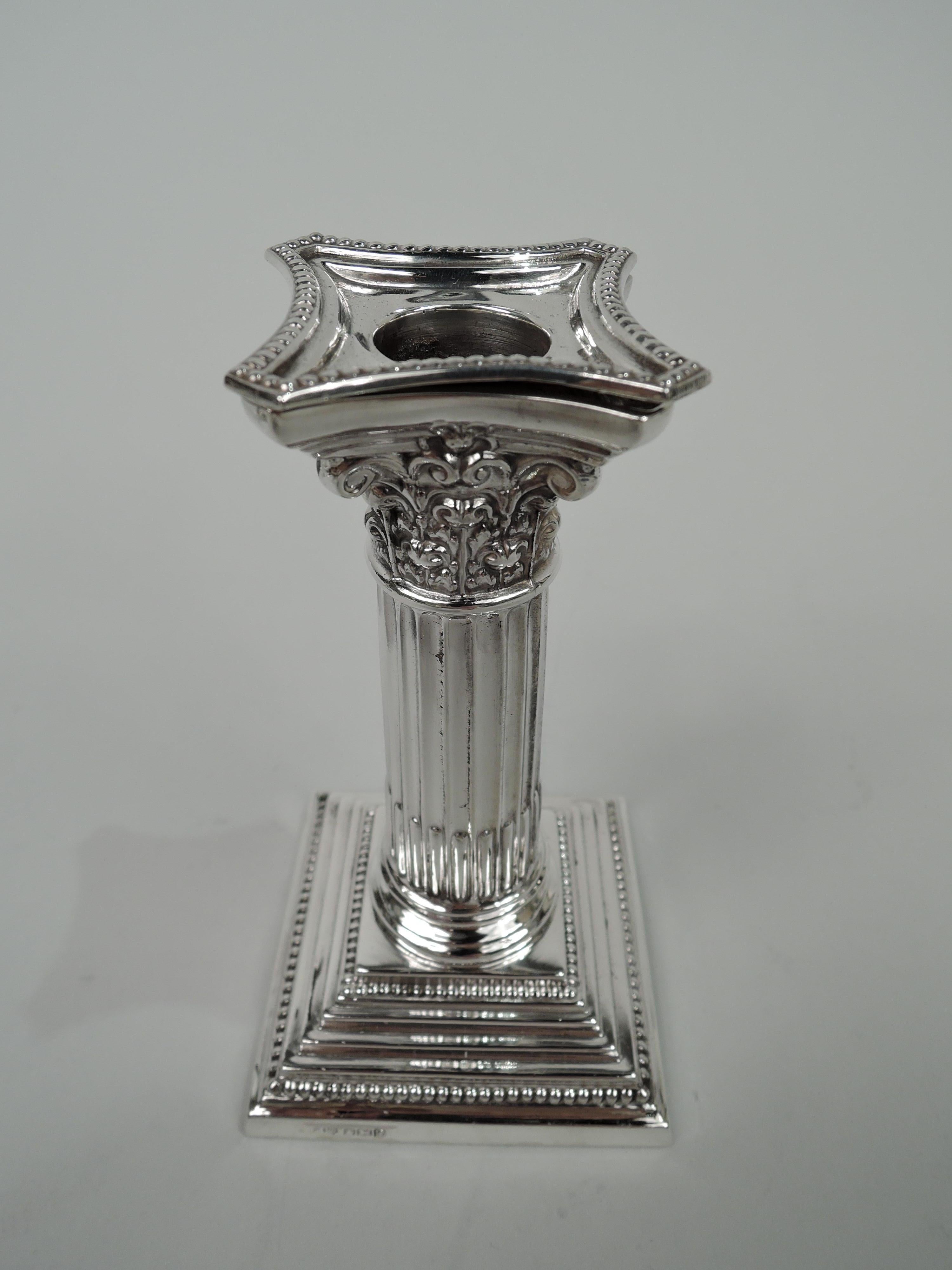 Pair of English Neoclassical sterling silver candlesticks, 1957-9. Each: Traditional column with stop-fluted shaft on stepped square foot. Composite Corinthian capital with concave sides and detachable bobeche. Beading. Fully marked including 1957