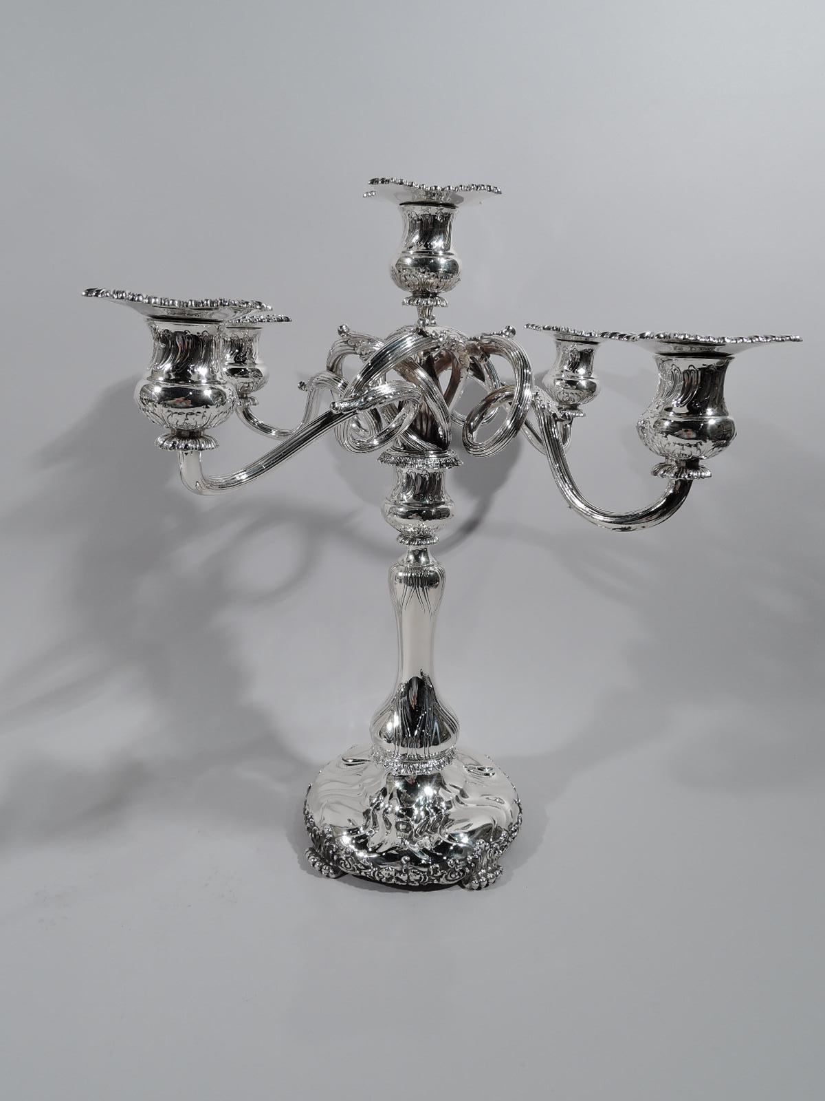 Pair of turn-of-the-century sterling silver 5-light candelabra. Made by Tiffany & Co. in New York.

Each: Urn socket on baluster shaft on wide and round raised base supported by 4 leaf-mounted paw supports. Detachable branches comprising ribbed