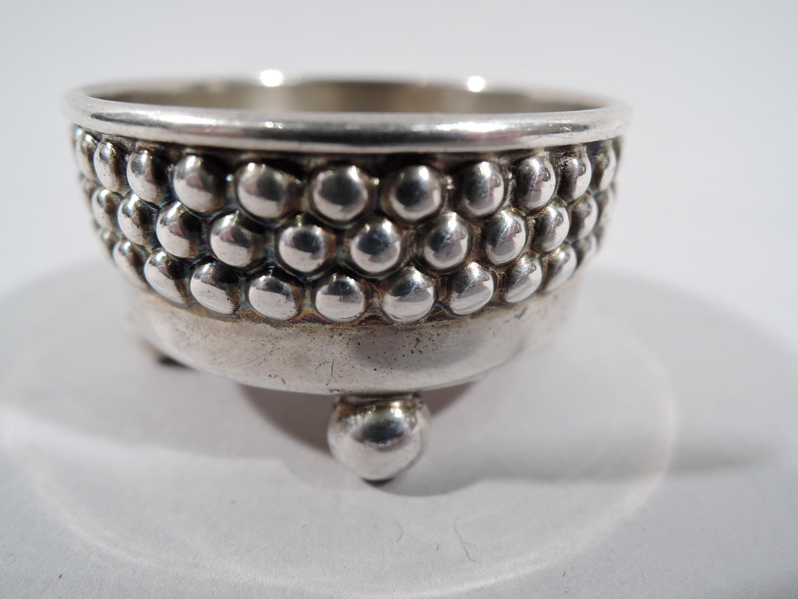 Pair of Victorian modern sterling silver open salts. Made by Tiffany & Co. in New York. Each: Round with straight sides and 4 ball supports. Sides exterior have three rows of beading, suggestive of ball bearings. An unusual design with an industrial
