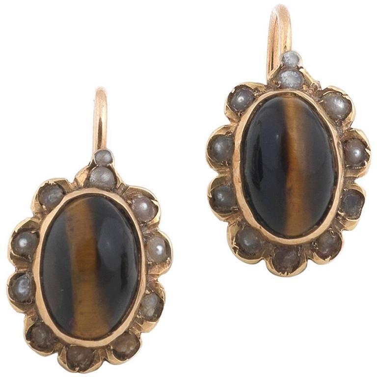 Set with an oval shape cabochon cut tiger eye within half pearl shape to a carved gallery.

Mounted in yellow gold

2 cm long (with the hook), tiger eye 1 cm long 

Weight: 3.7 gr
