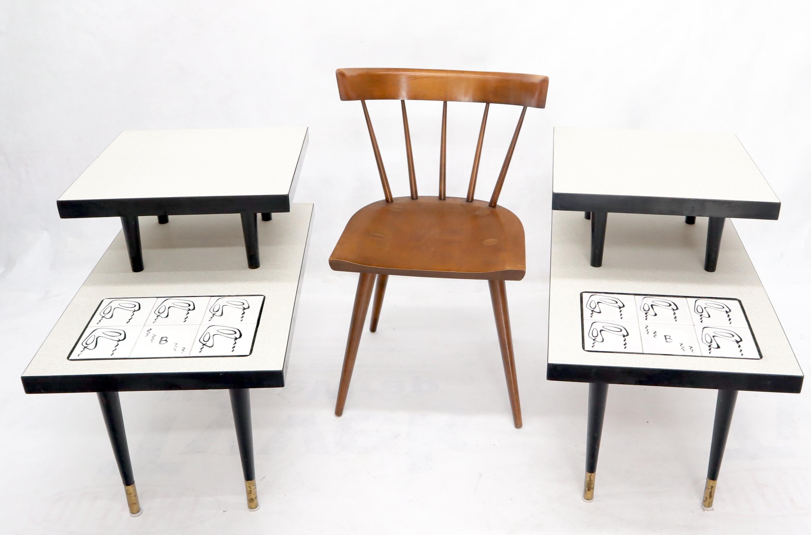 Mid-Century Modern pair of art tile step tables standing on dowel shape legs with brass legs tips. Solid heavy laminated hardwood construction.