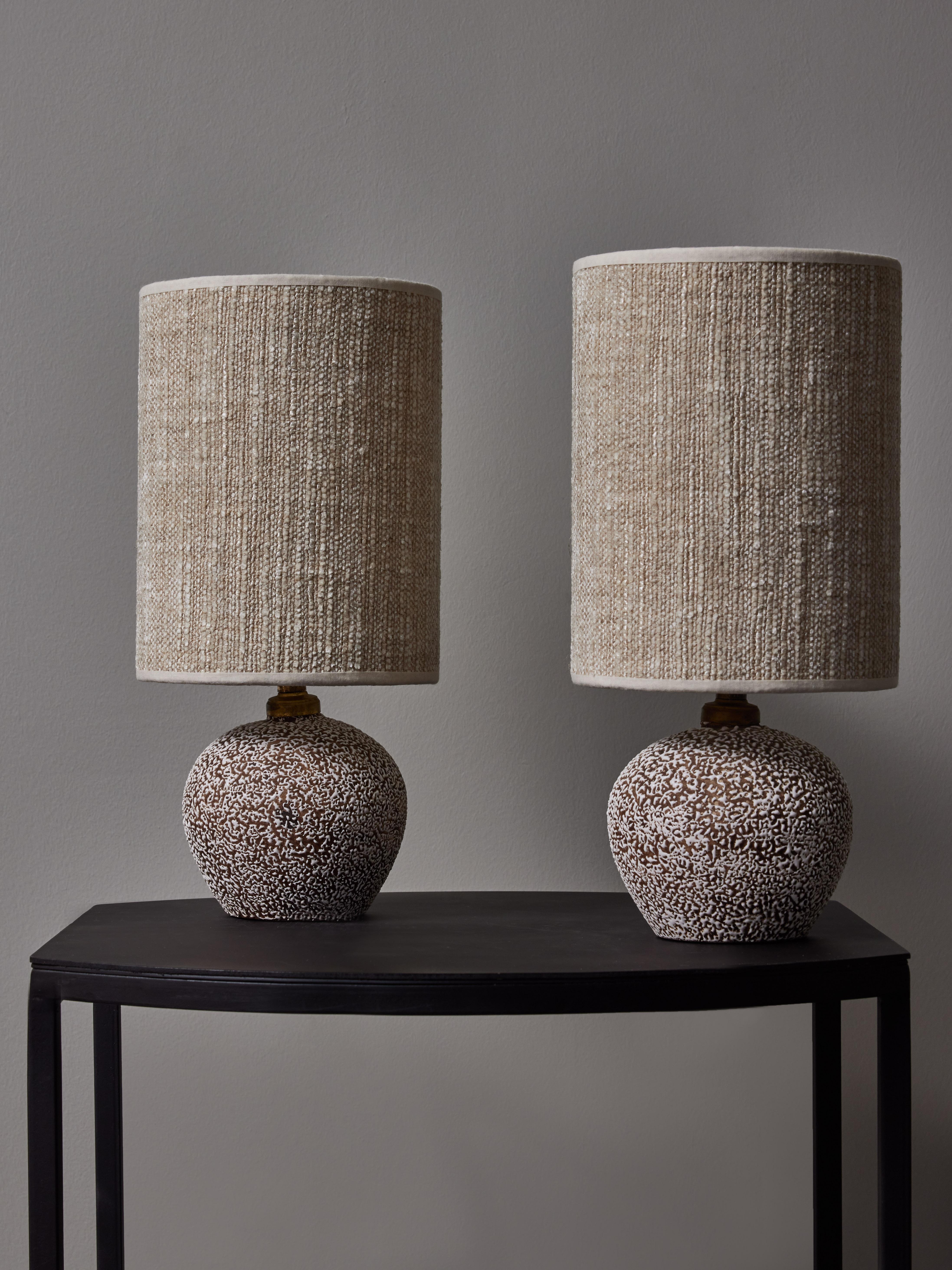 Small pair of round table lamps made of speckled ceramic topped with new shades.