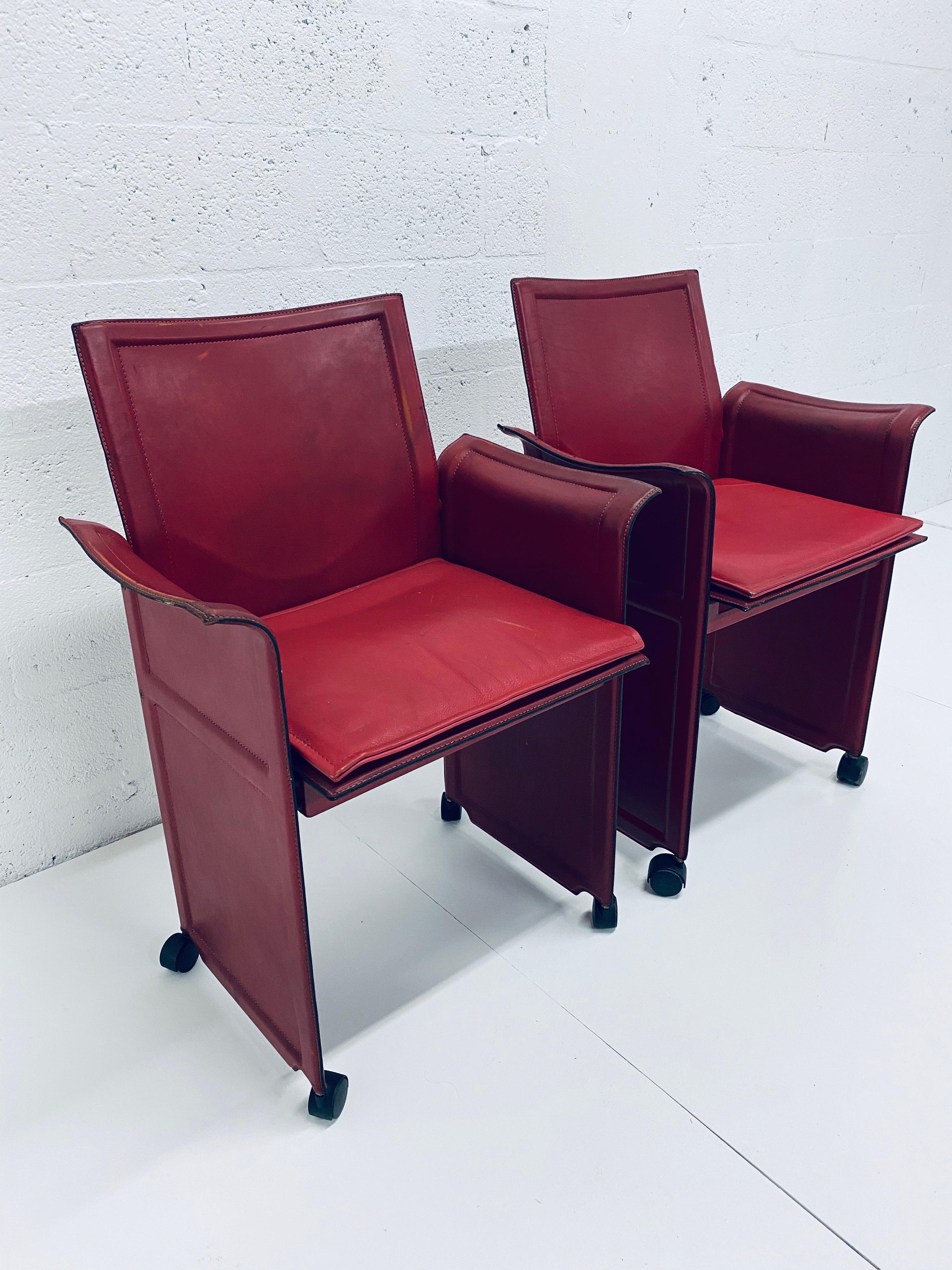 Pair of distressed red leather Korium chairs on removable casters by Tito Agnoli for Matteo Grassi. The arms have a wing like appearance and the seats come with an extra cushion for comfort.